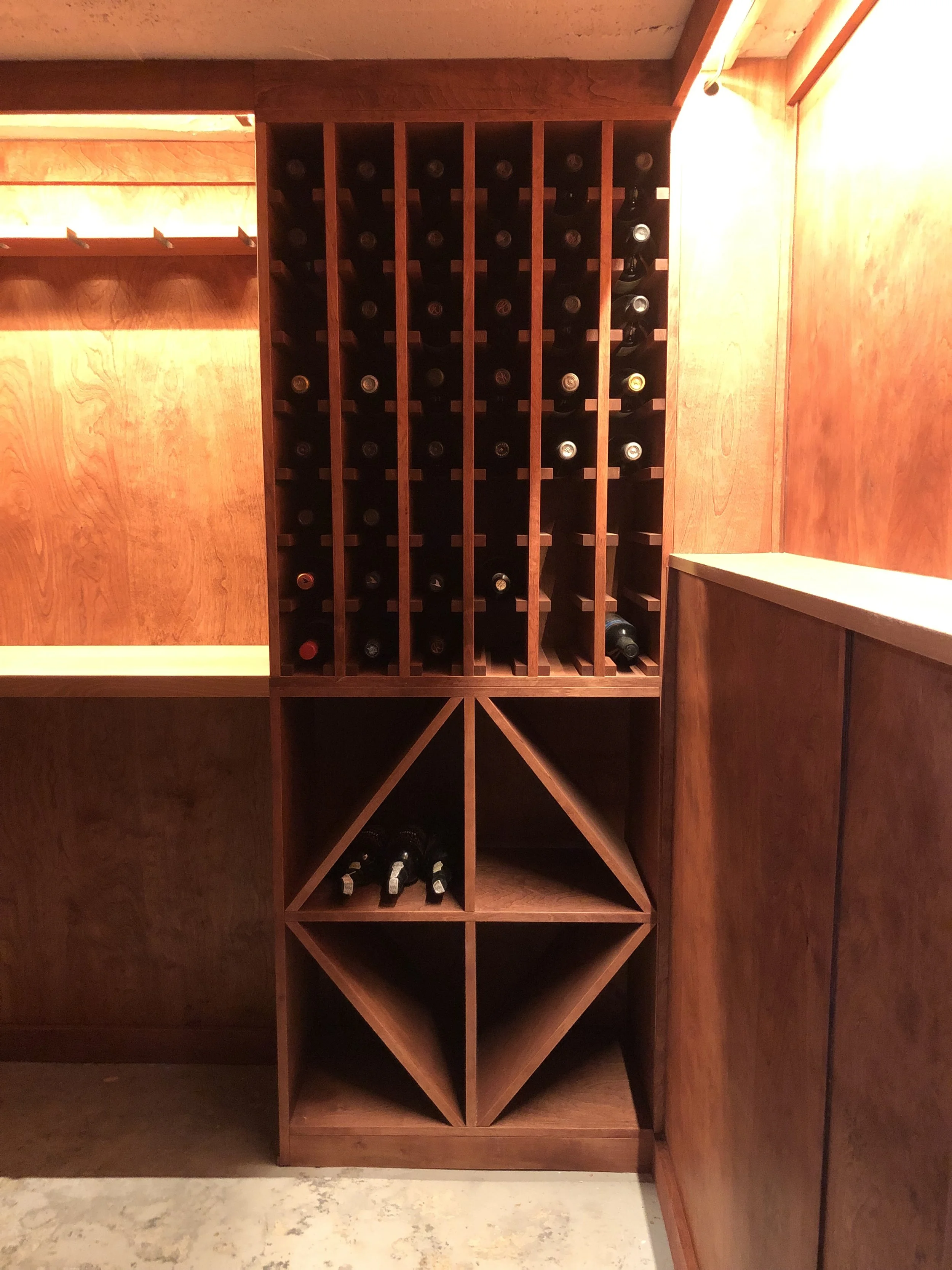 Wooden wine rack with bottles stored horizontally in a room with wooden walls.
