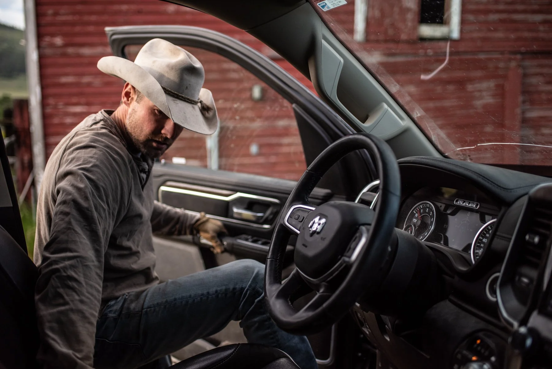A man wearing a cowboy hat leaning into the driver’s seat of a truck.