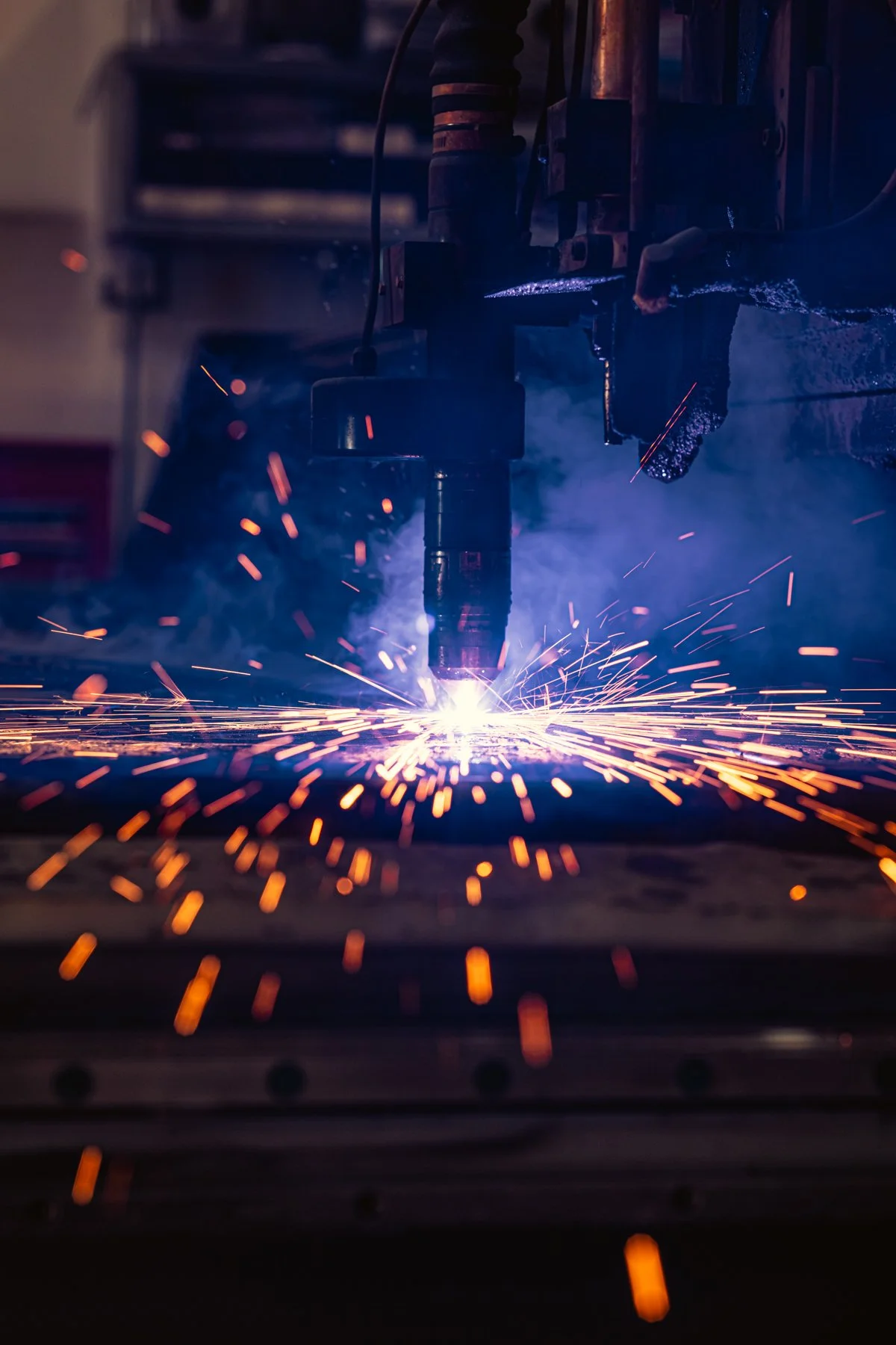 Welding process with sparks flying as a machine welds metal together in a workshop.