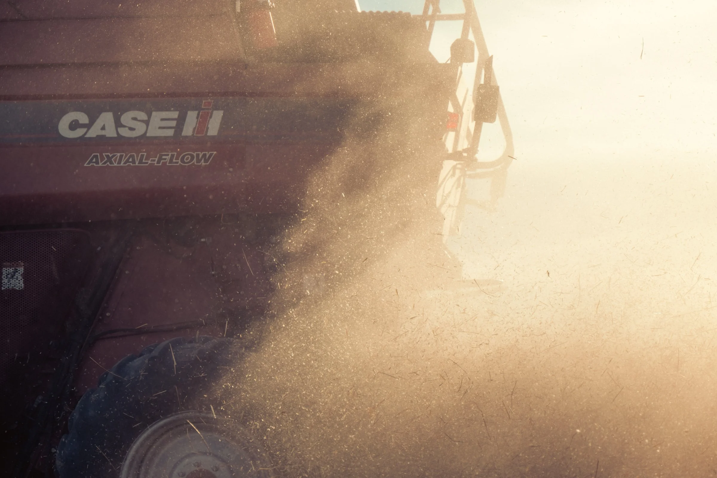 Close-up of a red CASE IH tractor with dirt and dust on it, in a dusty environment.