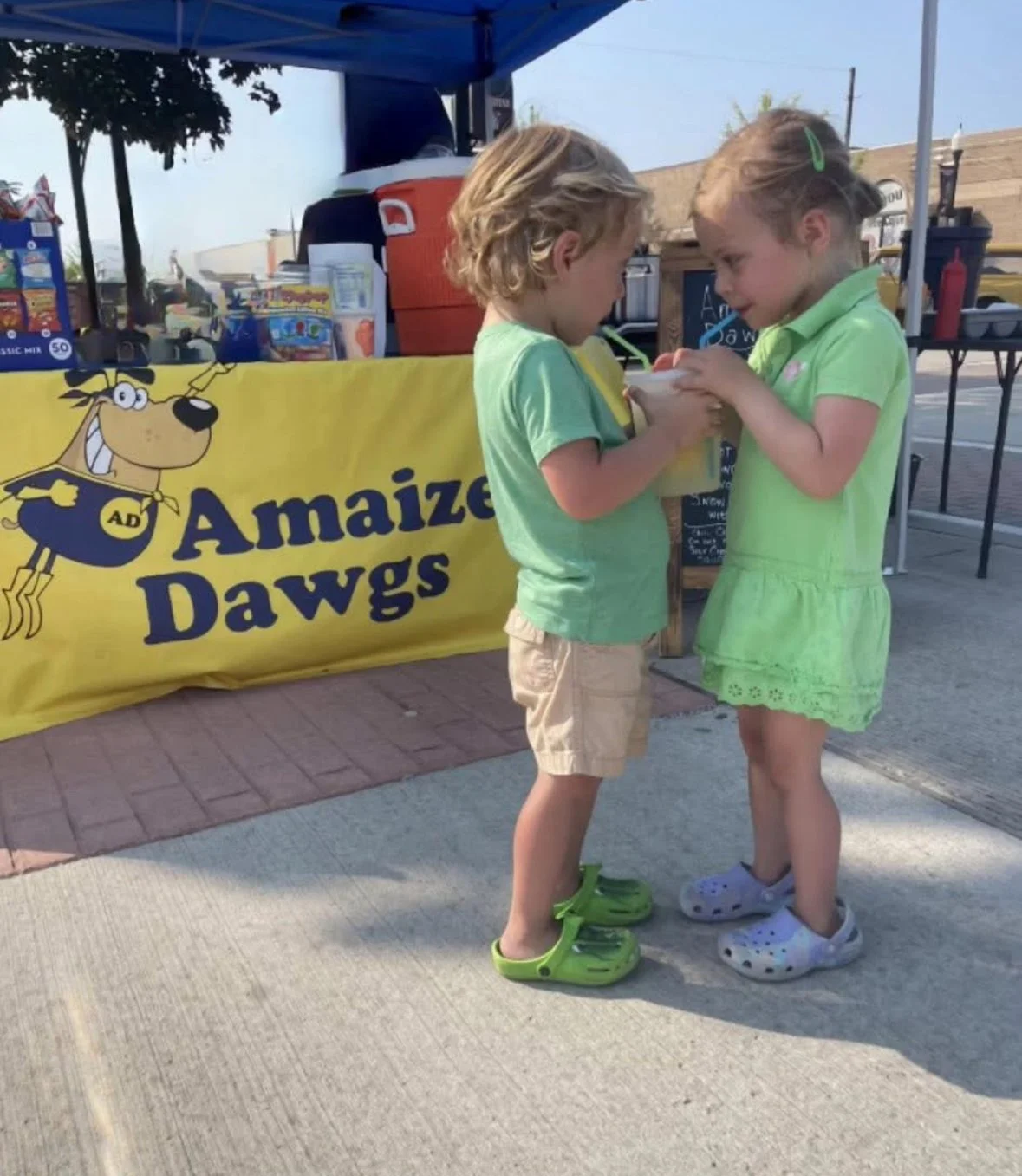 Two children sharing a beverage with two straws