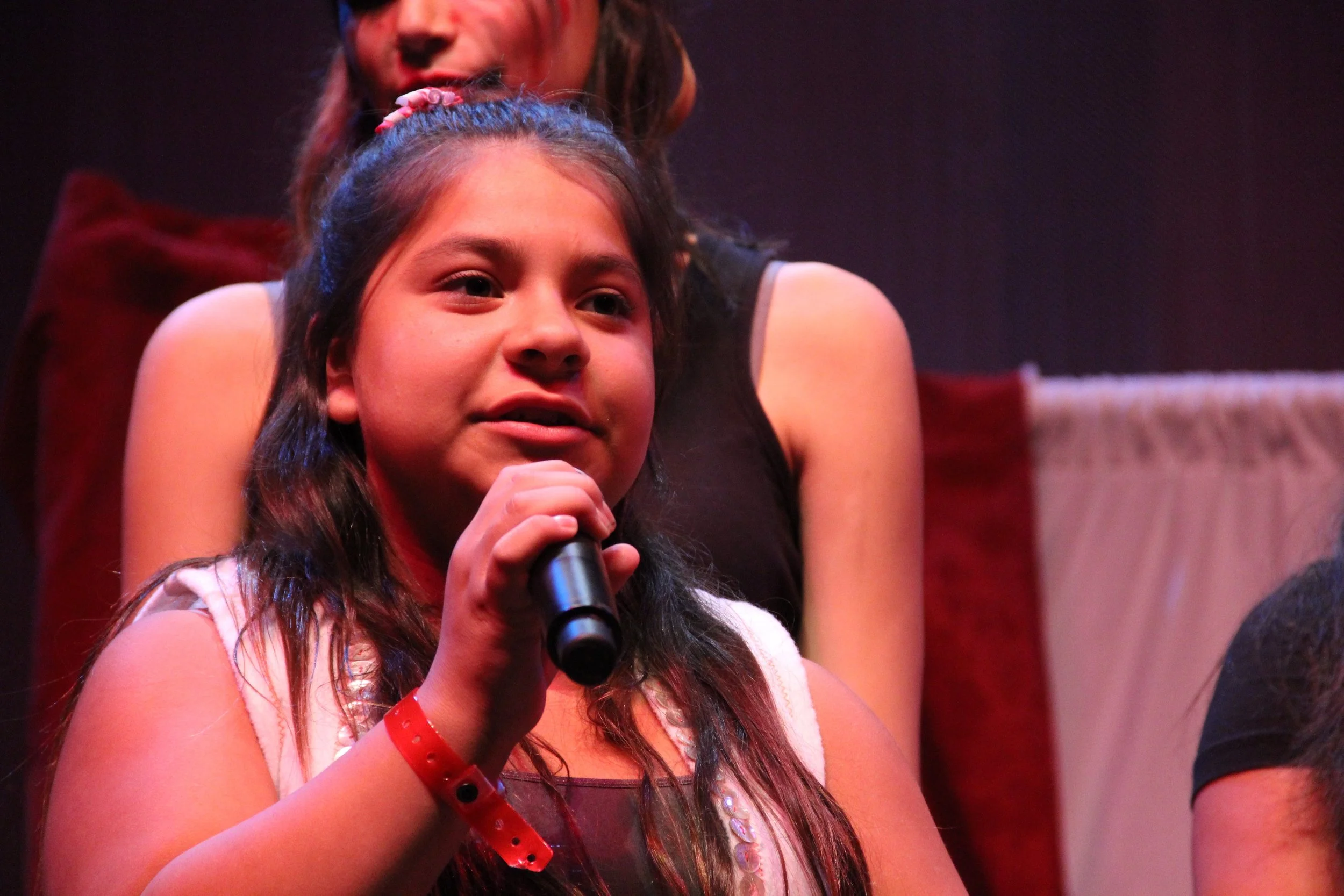 A Red Eagle Soaring youth singing into a microphone with another girl in the background.