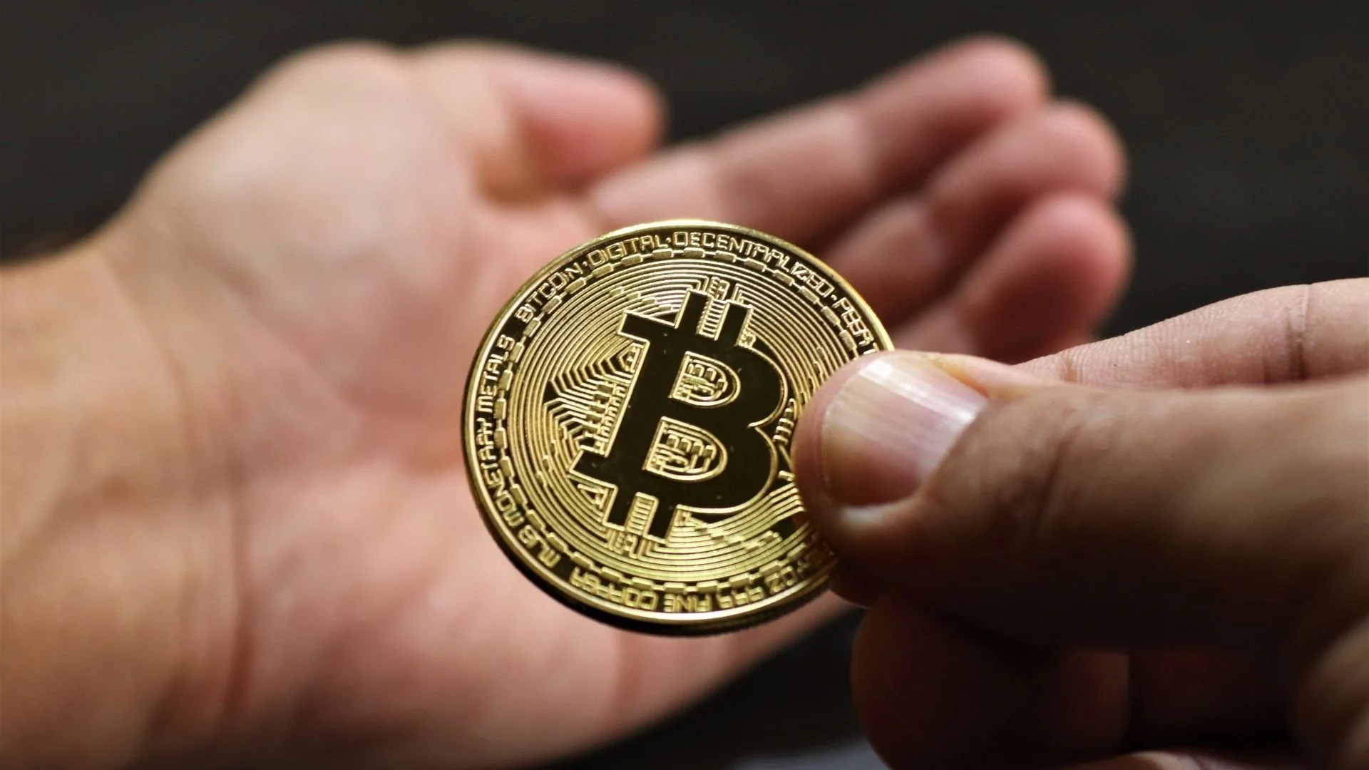 Close of someone holding a bitcoin in their hand