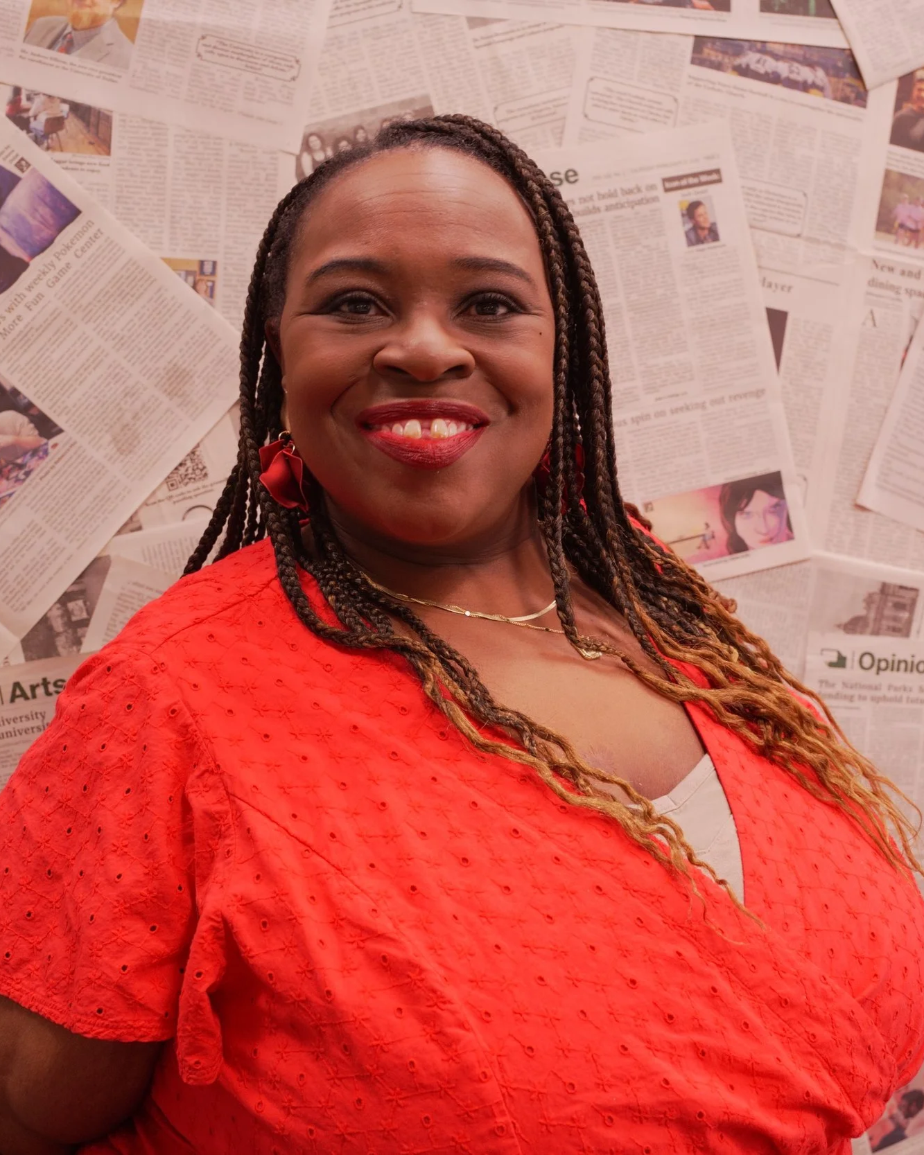 Clinician smiling during a professional portrait in front of a newspaper backdrop.