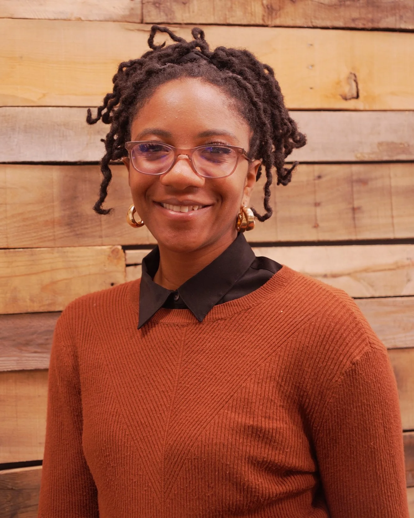Clinician smiling during a professional portrait against a wooden backdrop.