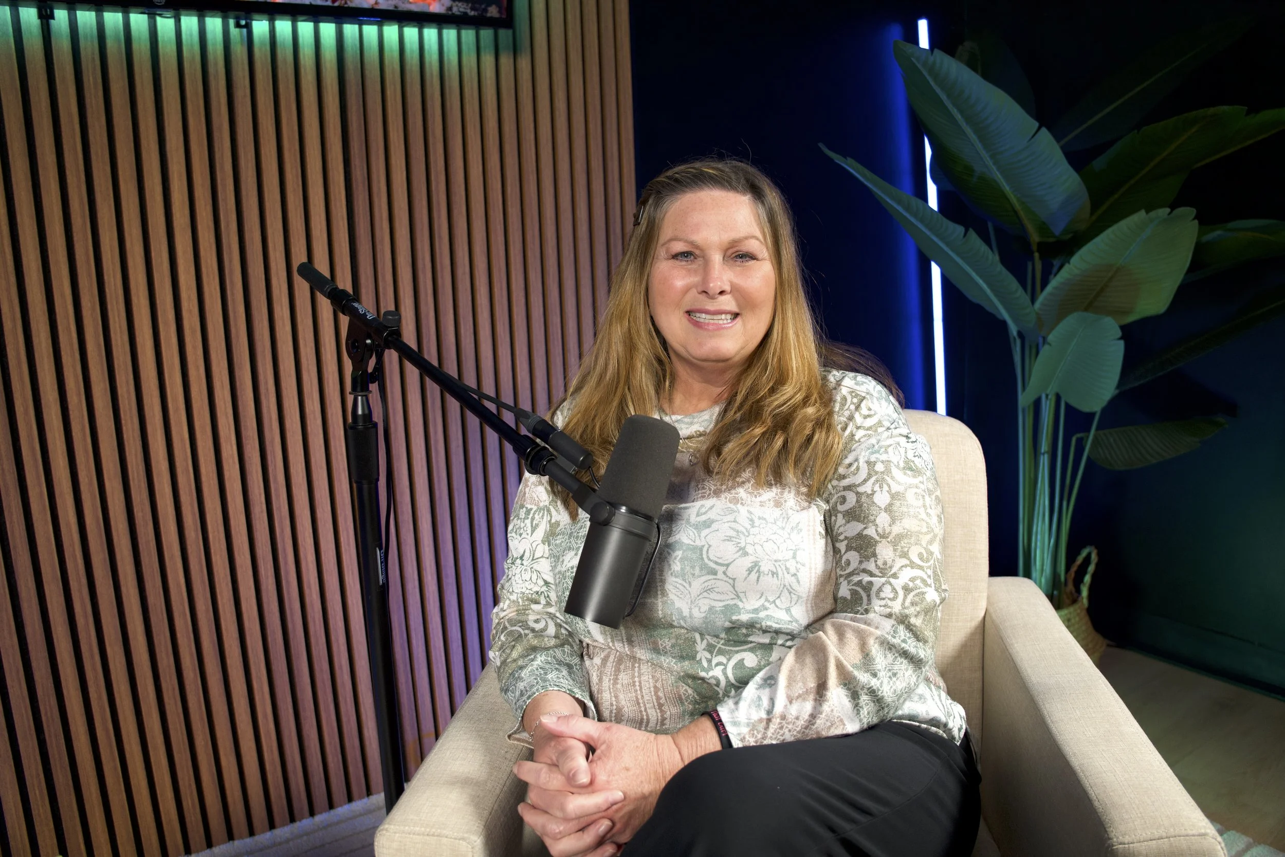 Clinician seated in a recording studio, smiling during a counseling podcast conversation.