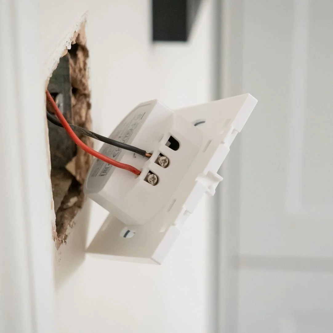 Close-up of an electrical outlet being installed into a wall with wires connected.