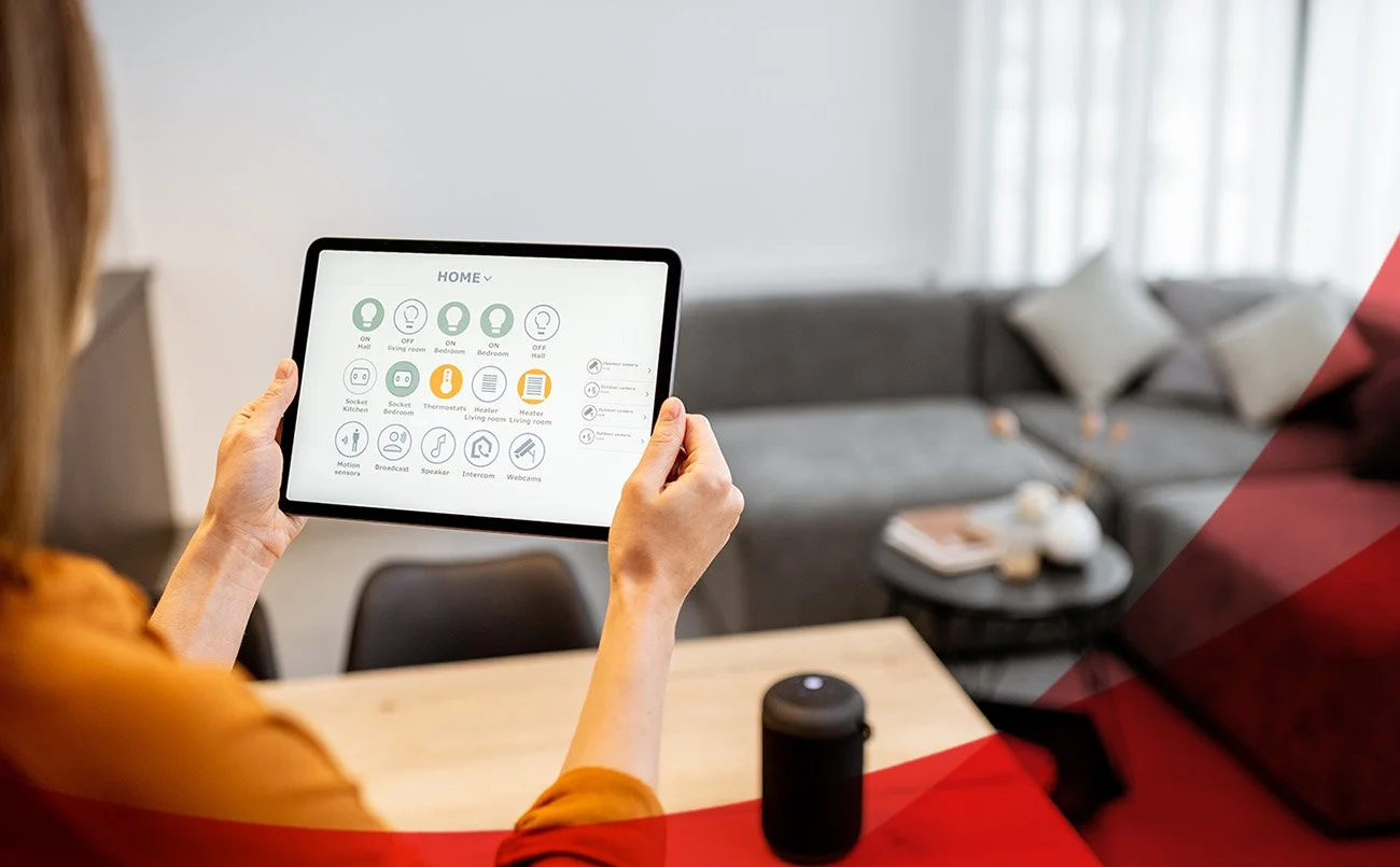 Person holding a tablet in a living room with smart home control app displayed.