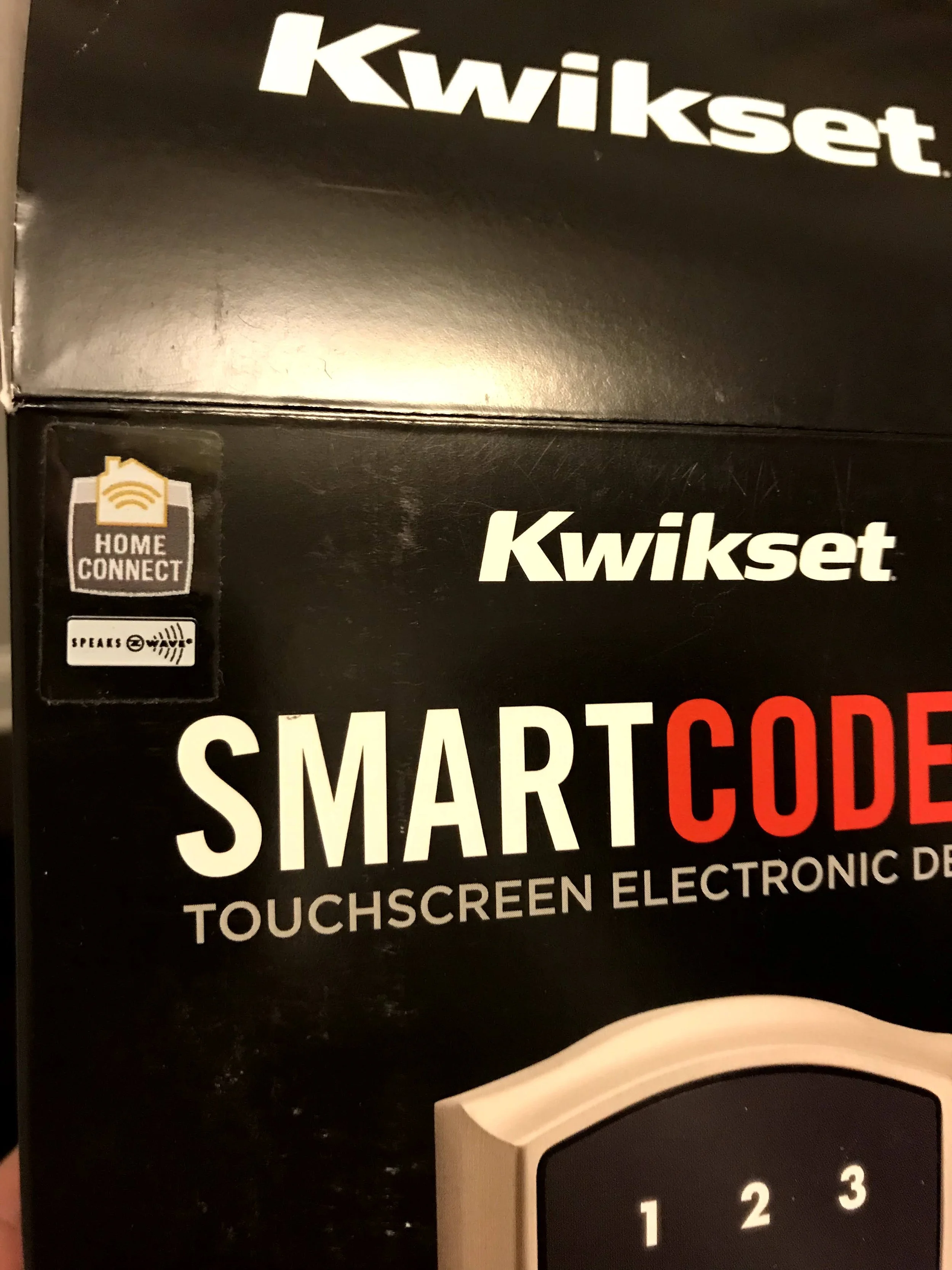 Close-up of black packaging for Kwikset SMARTCODE touchscreen electronic deadbolt, showing the Kwikset logo and product details.