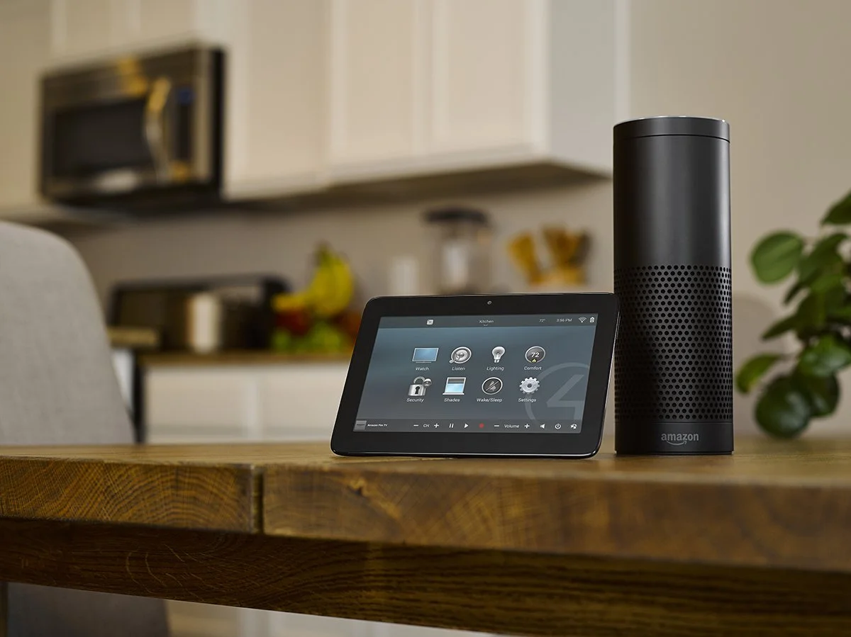 Amazon Echo speaker and a smart display on a wooden table in a kitchen.