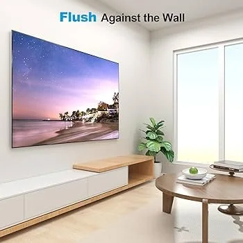Living room with a wall-mounted TV displaying a beach scene, a wooden console, a potted plant, and a round wooden table with a bowl and books.