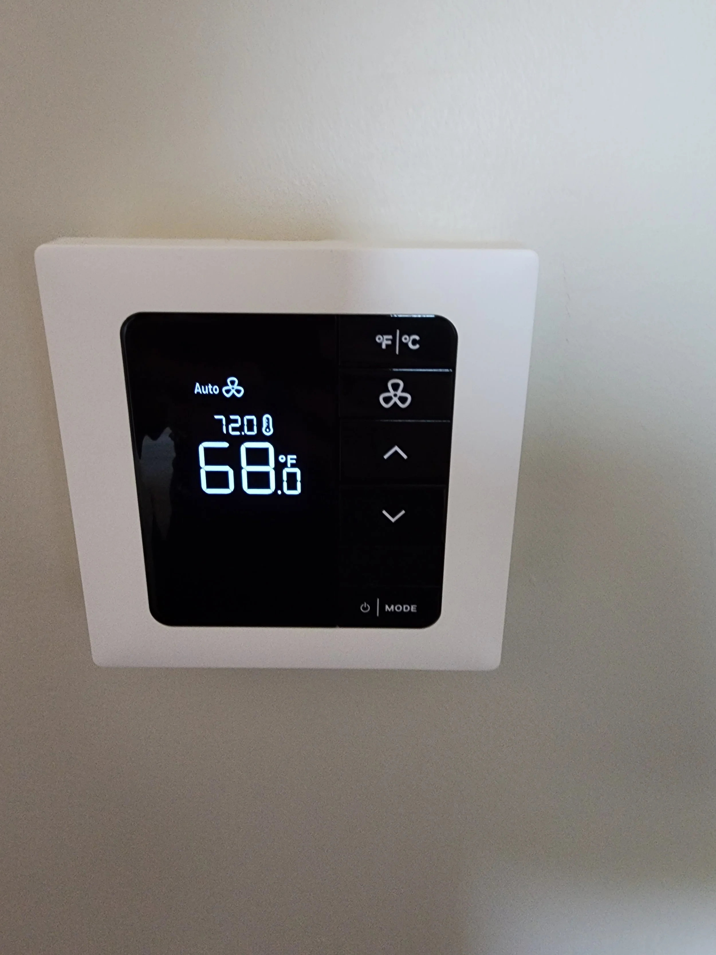 A digital thermostat mounted on a wall displaying the temperature as 68 degrees Fahrenheit, with controls for temperature, fan speed, and mode.
