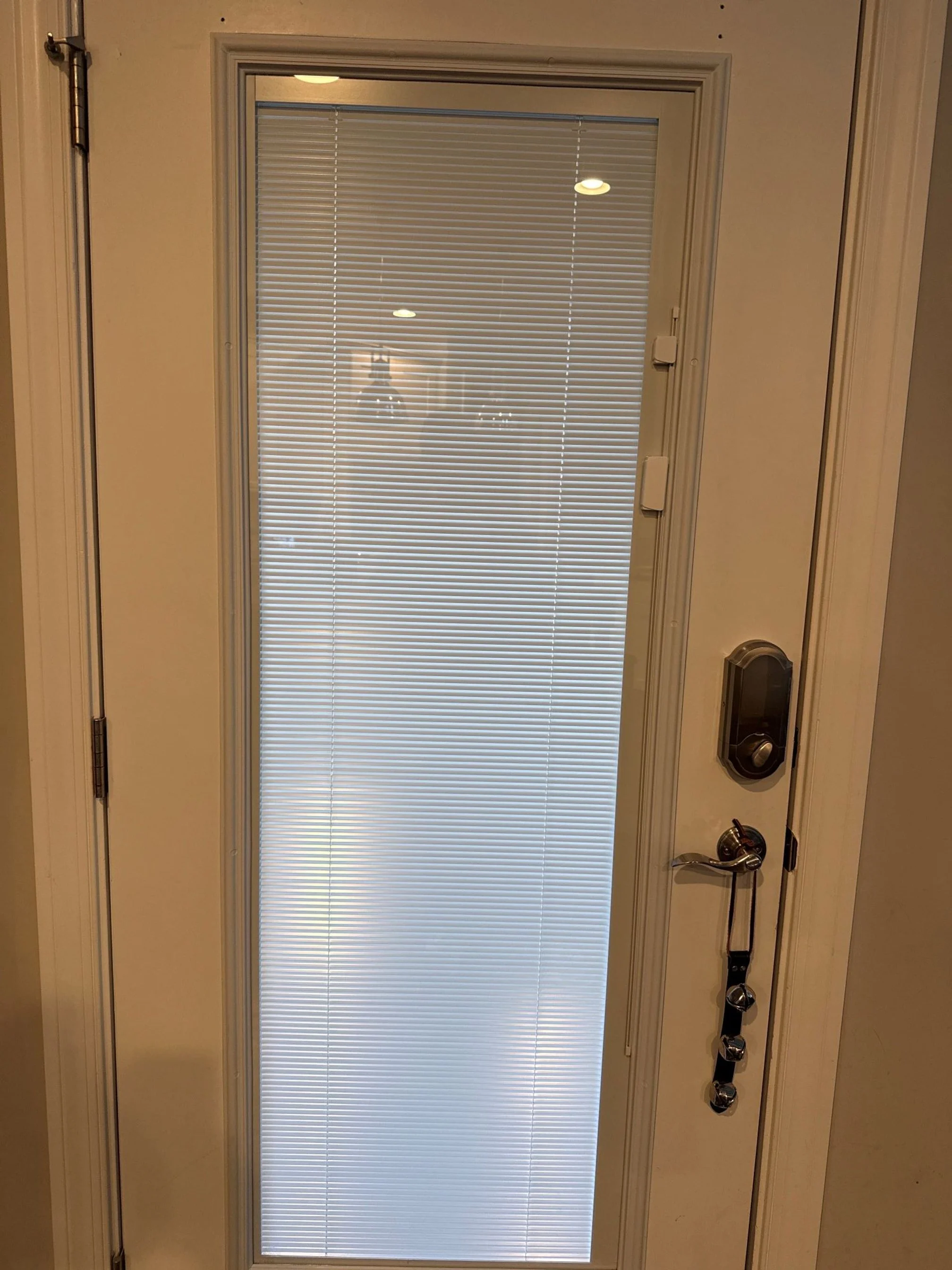 Screened door with white window blinds inside, a lock, a handle, and a keychain hanging from the handle.