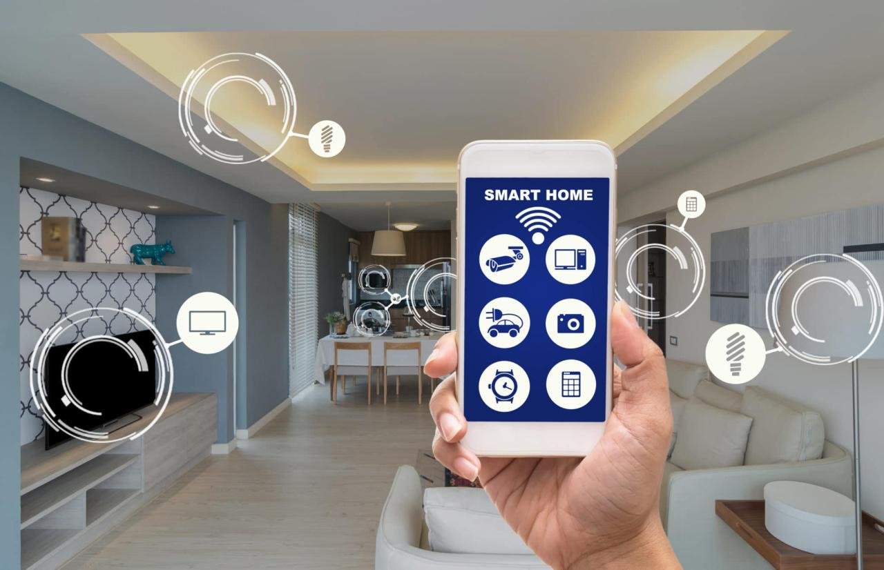A person holding a smartphone displaying a smart home app with icons for various connected devices. The background shows a modern living room and dining area with digital overlays of smart home icons and controls.