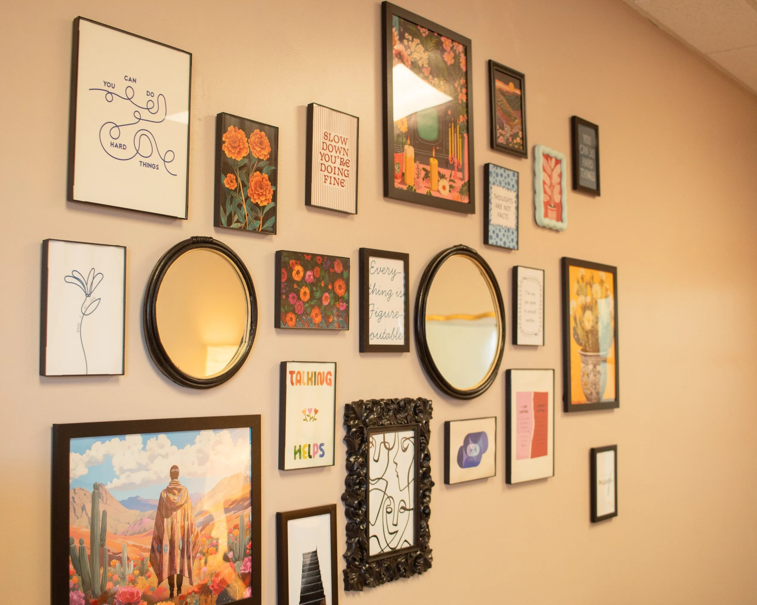 Decorative wall gallery with various framed pictures, motivational quotes, floral artwork, mirrors, and illustrations in a cozy room.