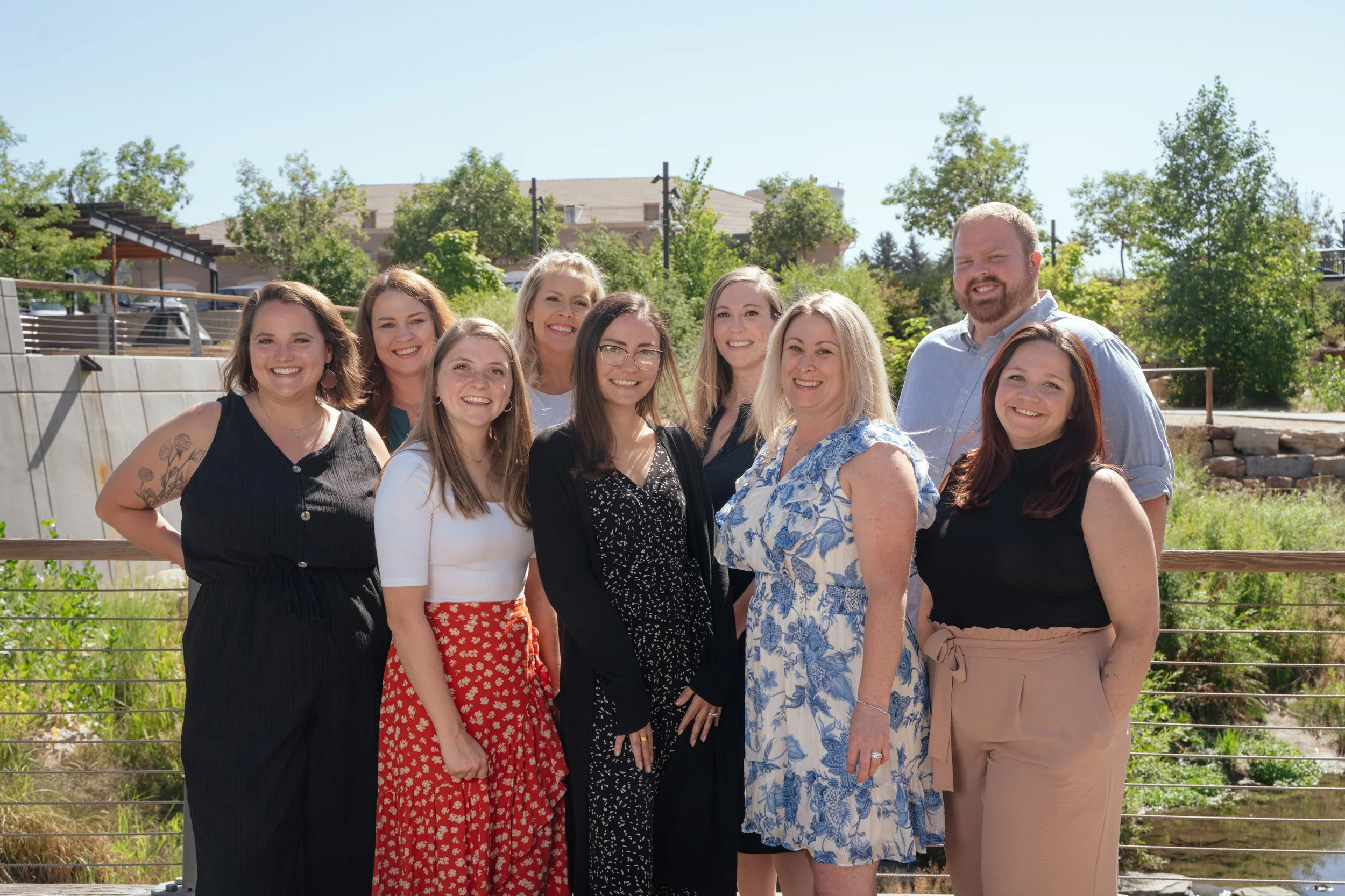 Group of therapists standing outdoors on a sunny day, with trees and buildings in the background.