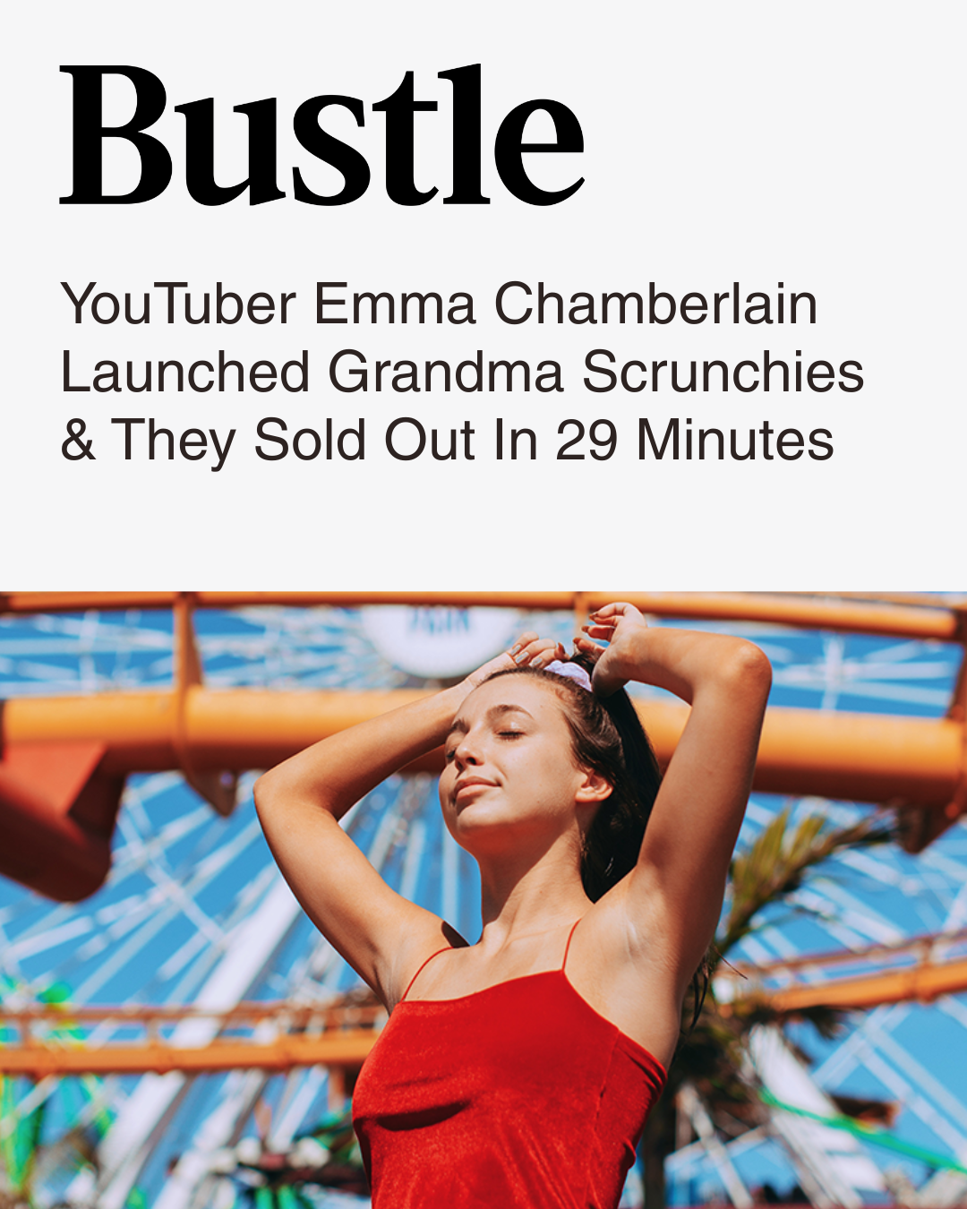 Bustle article featuring YouTuber Emma Chamberlain. Image shows Emma in a red dress with eyes closed, posing with arms raised behind head at an amusement park with a ferris wheel in the background.