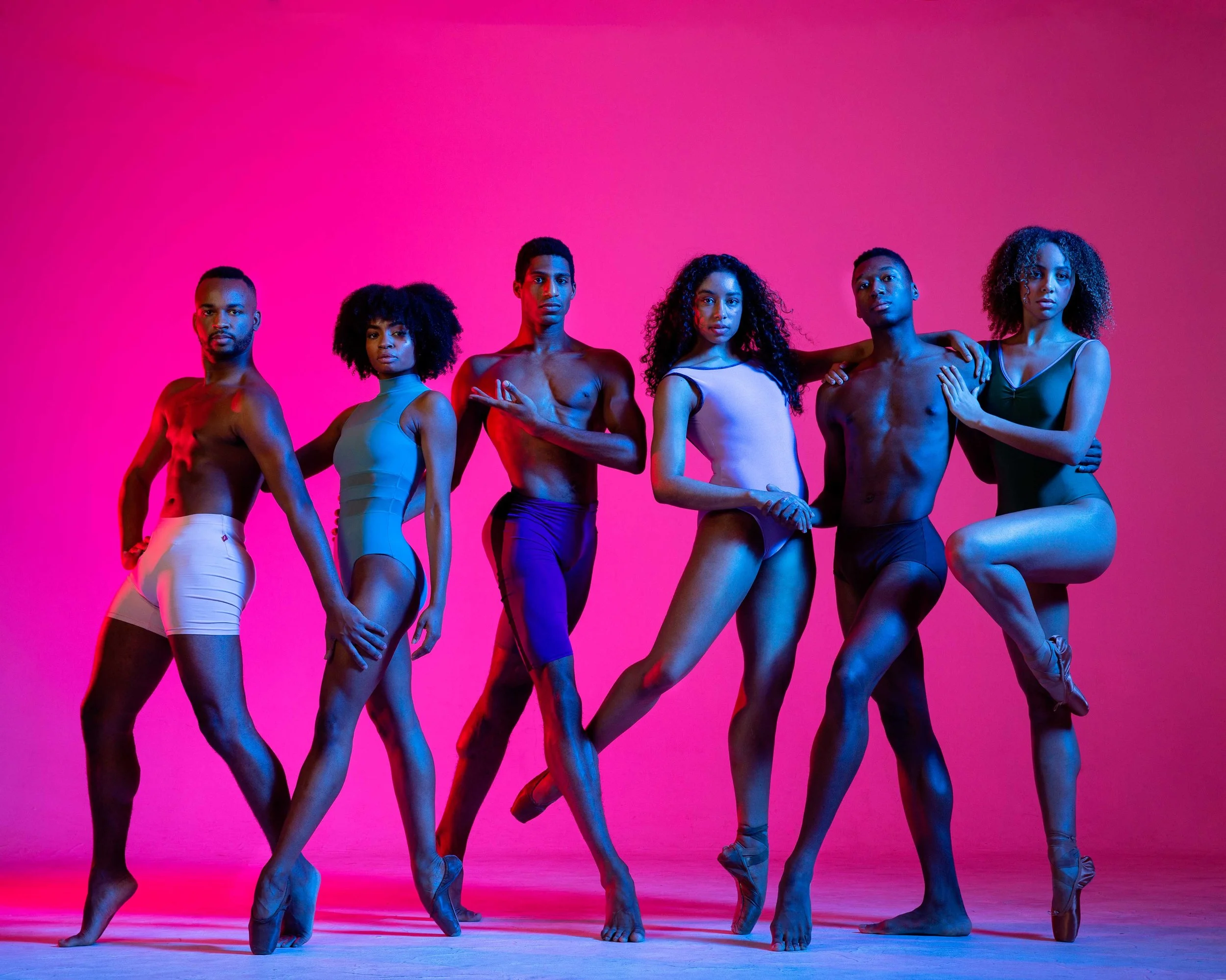 Six diverse Shades Dance Theater dancers in varied ballet poses against a pink gradient background.