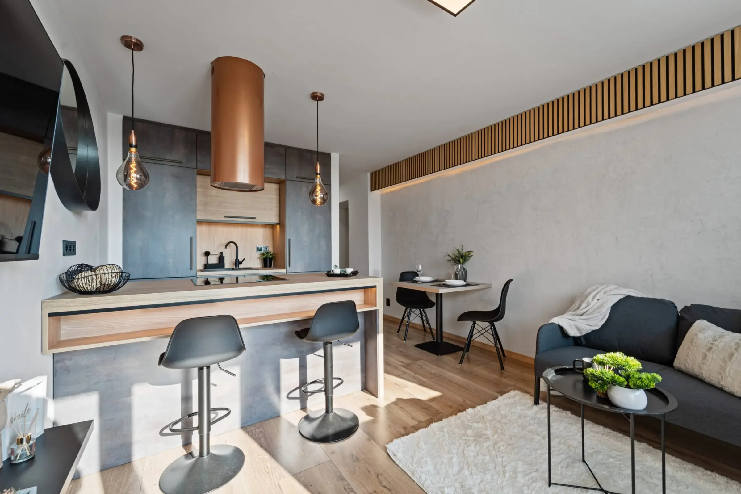 Modernes Wohnzimmer mit offener Küche, Esstisch, Sofa, Holzboden, und dekorativen Elementen.