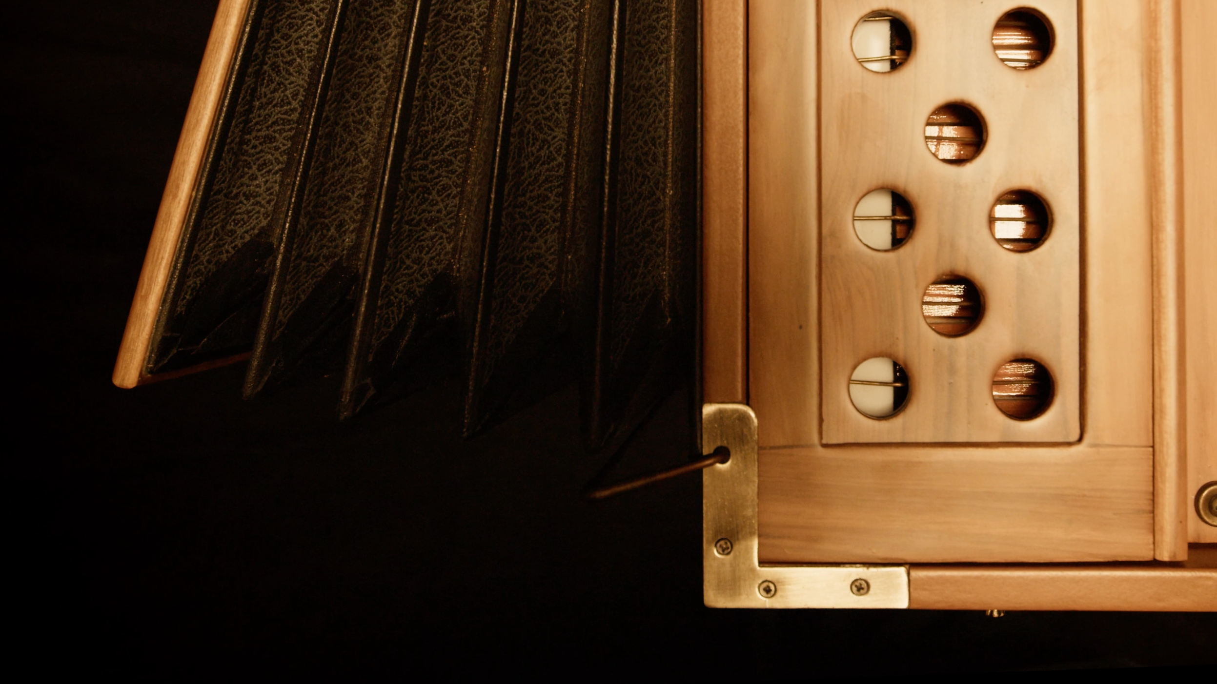 Close-up of a wooden pedal harmonium with sound holes and a part of the jaali