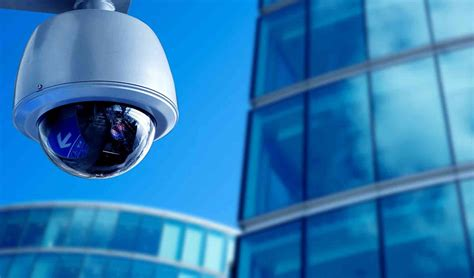 A security camera mounted on a building with reflective glass windows.