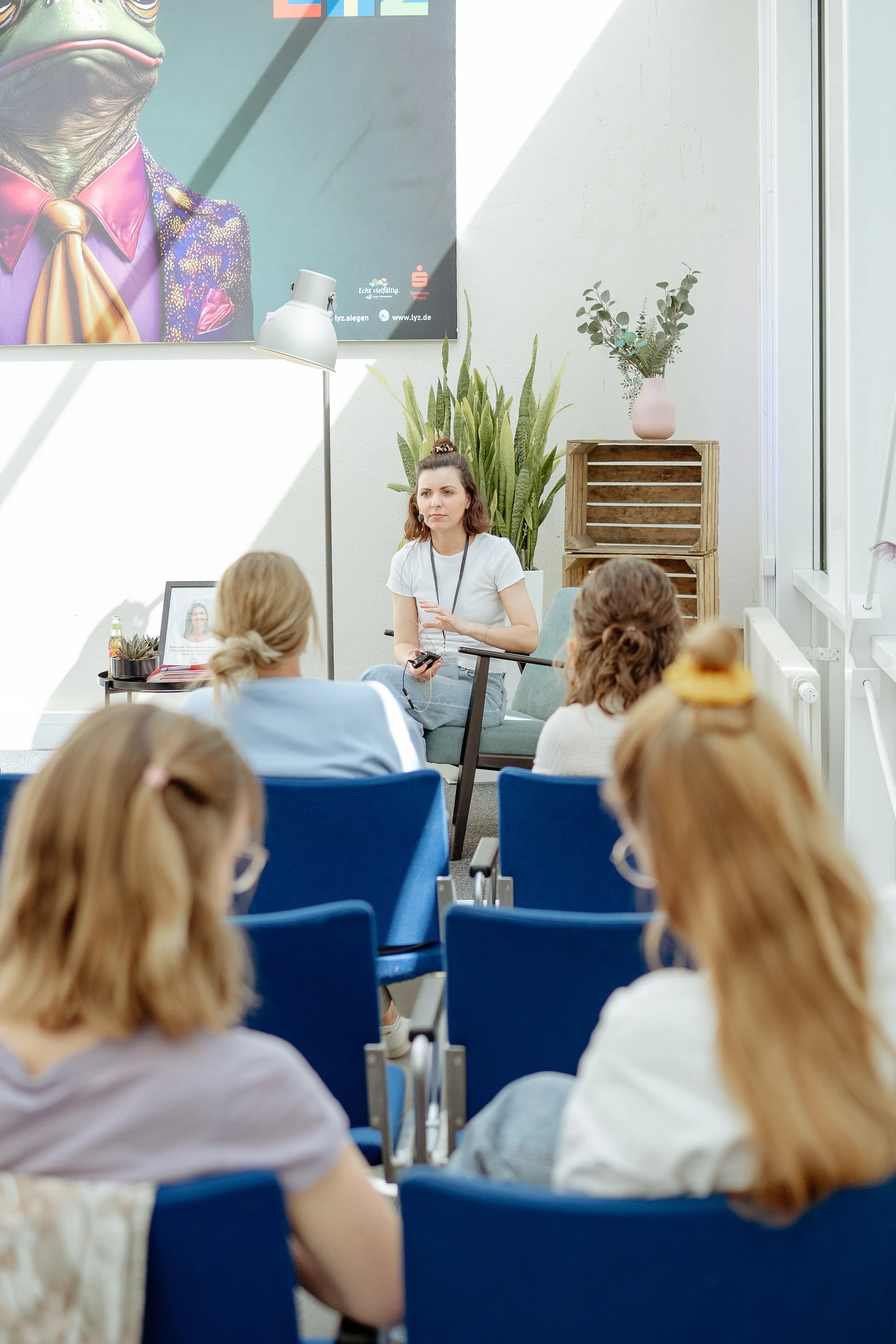 Frauen hören Vortrag auf Female Health Festival an, Speakerin sitzt auf der Bühne
