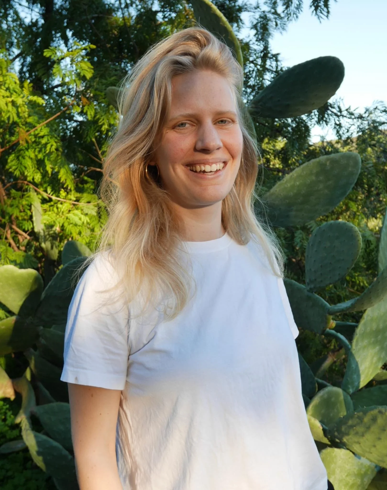 Blonde Frau schaut lächelnd in die Kamera.