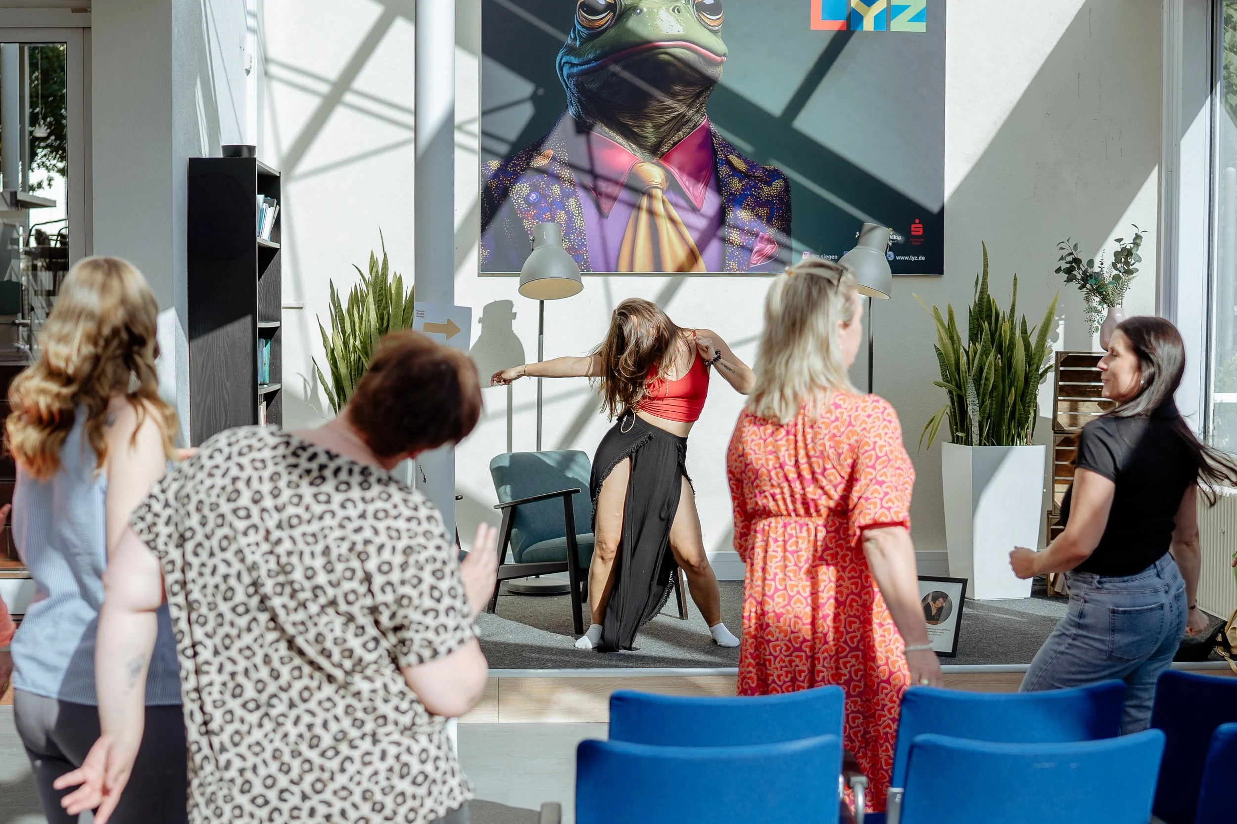 Frauen beim Tanzen vor der Bühne beim Female Health Festival. Angeleitet von einer Frau auf der Bühe mit langem Rock