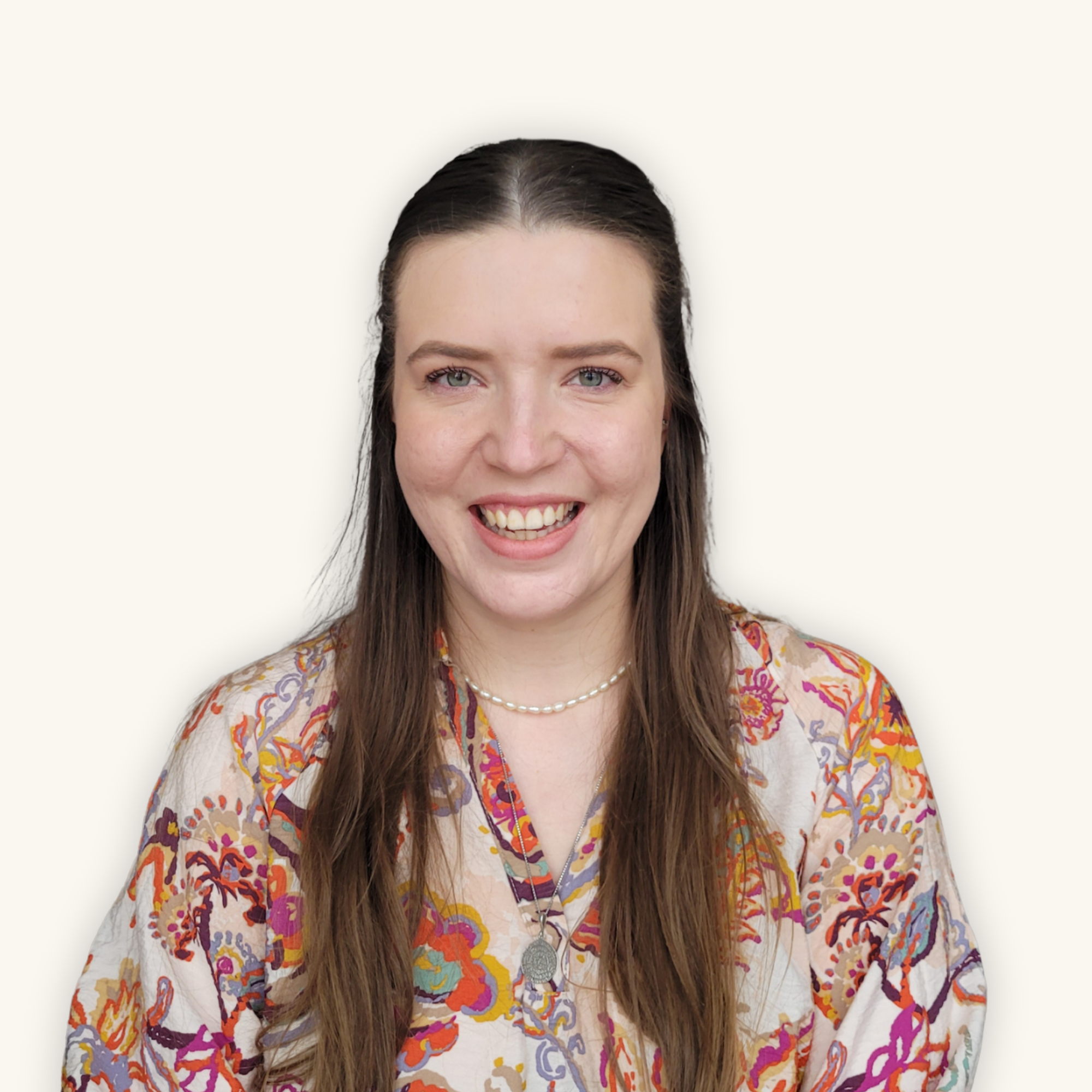 Junge Frau mit braunen Haaren und Mittelscheitel schaut frontal lächelnd in die Kamera.