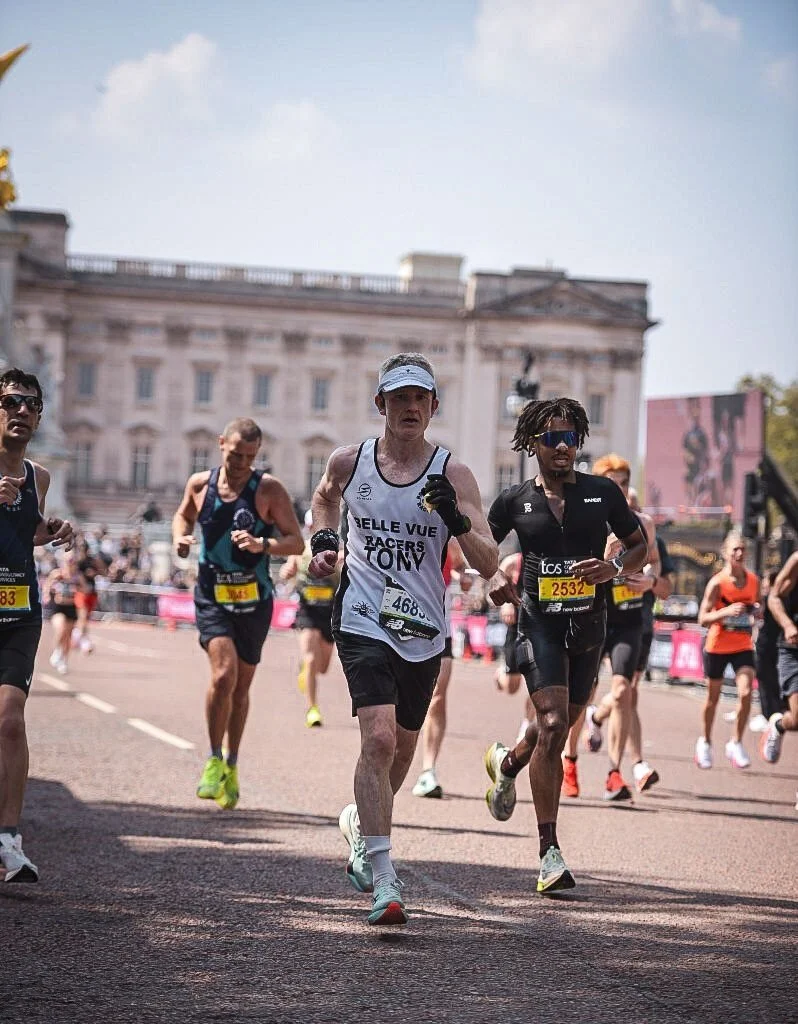 Group of marathon runners participating in a race on a city street with historic buildings in the background.