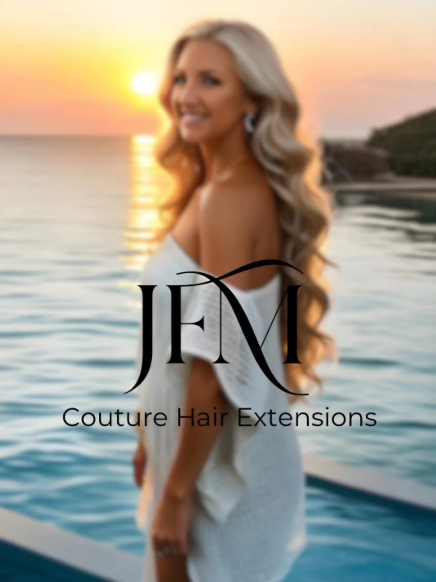 A woman with long blonde hair in a white dress standing by the water during sunset with the logo 'JFM Couture Hair Extensions' overlaid on the image.