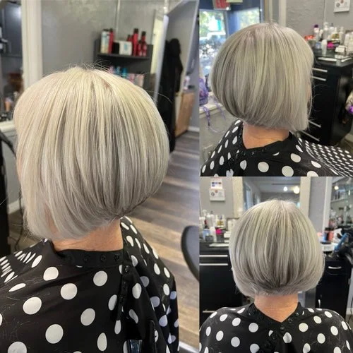 Short, layered silver blonde bob haircut on a woman in a salon.