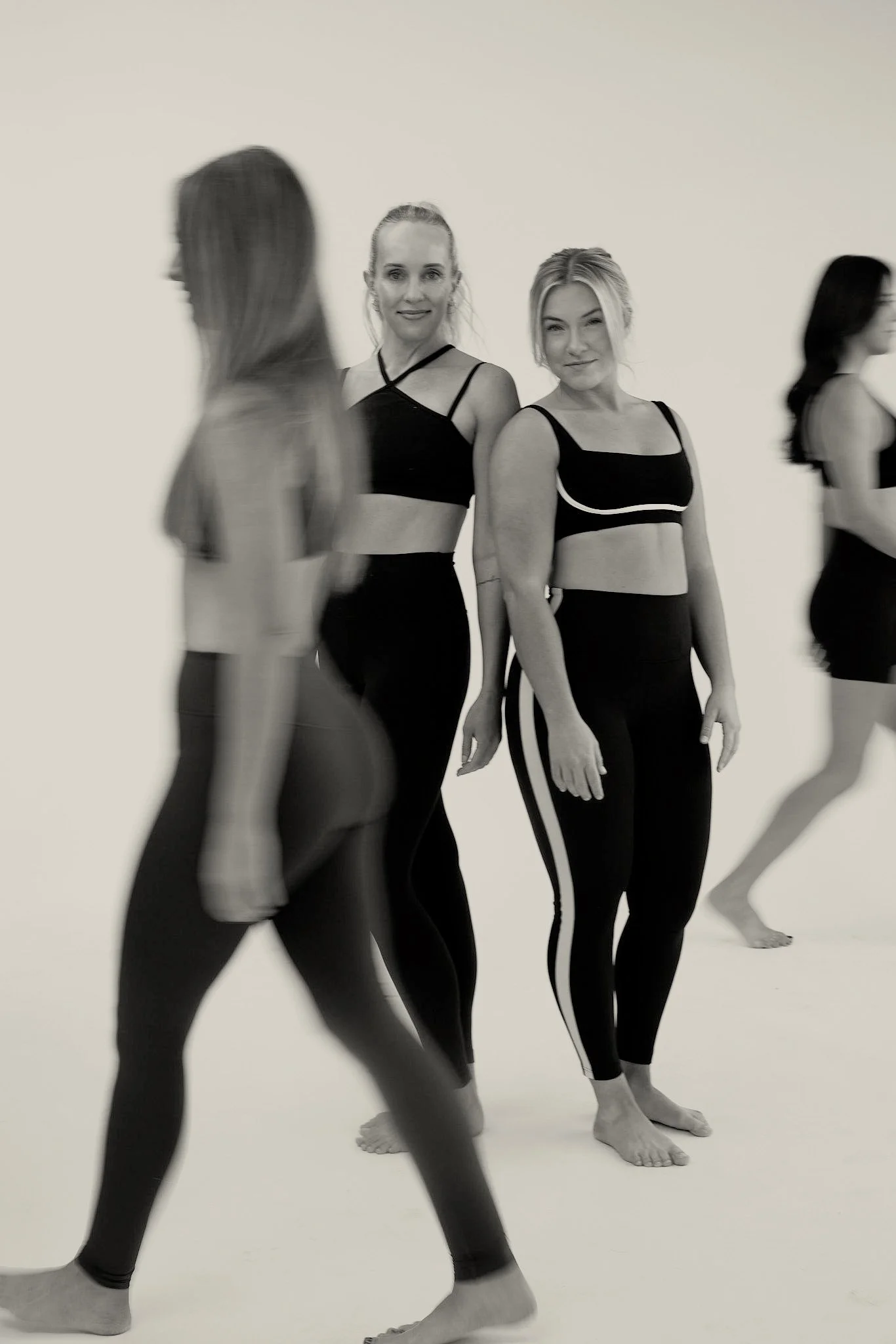 Group of women in black workout outfits standing in a studio.