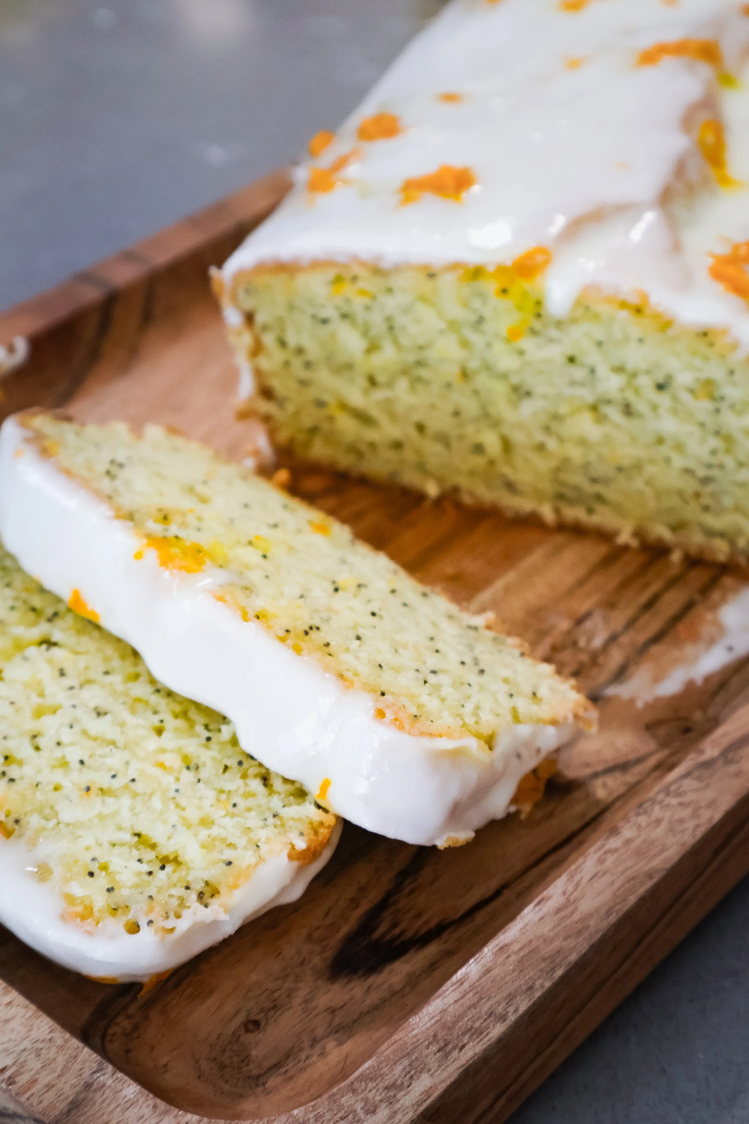 Close up of Orange Poppyseed Bread topped with icing and orange zest & sliced 