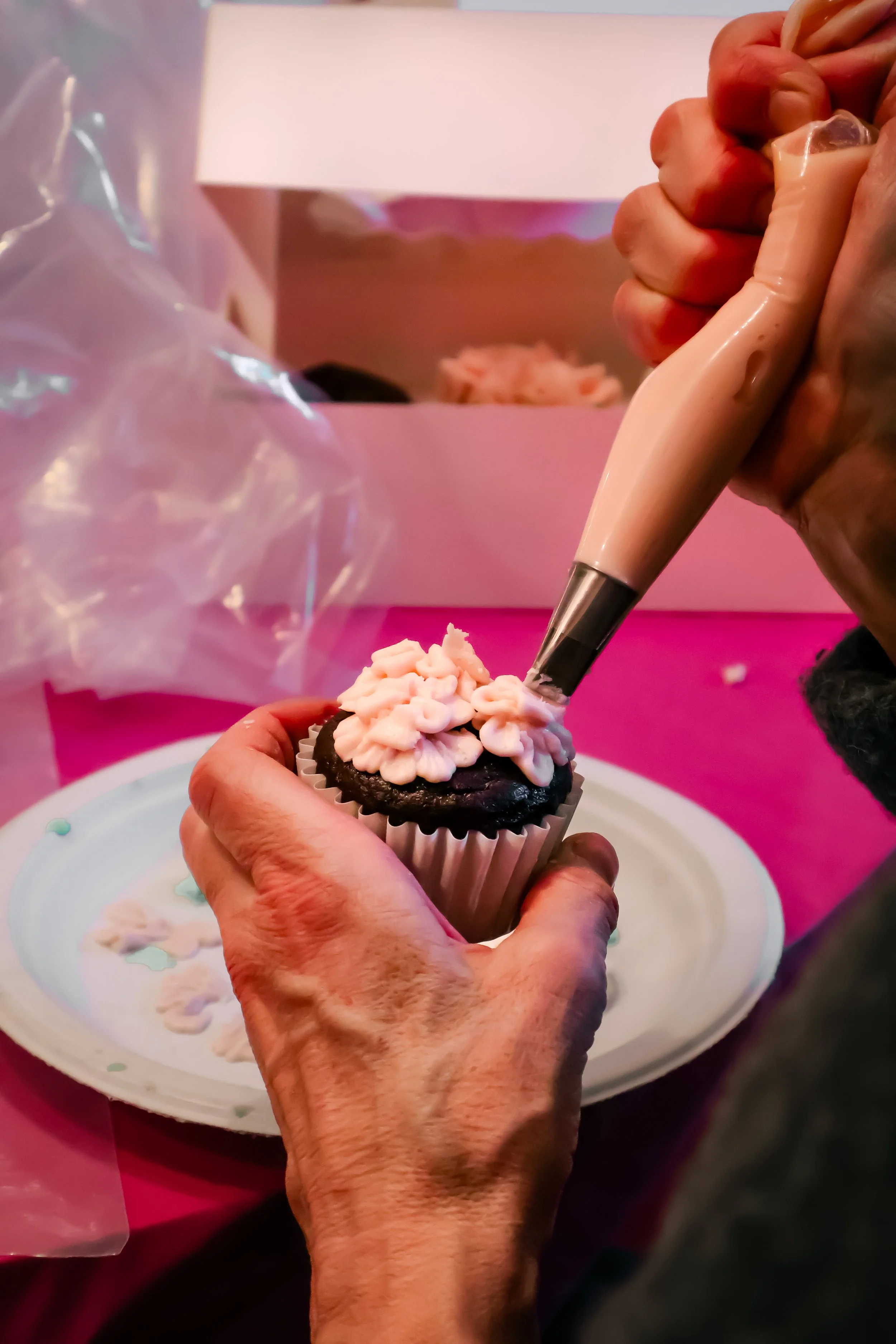 Hands decorating GF cupcakes at event