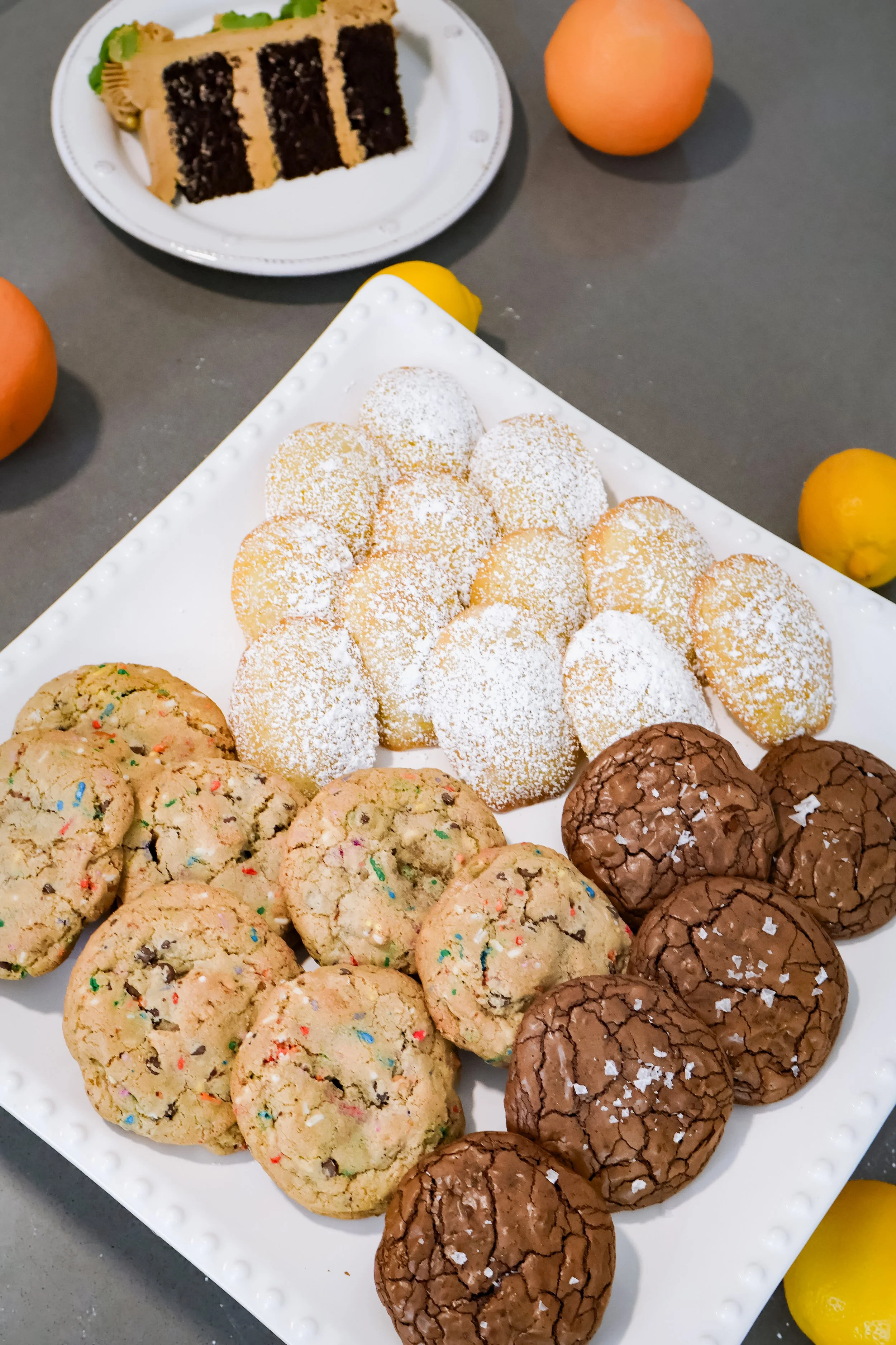 A close-up view of freshly baked chocolate chip, brownie batter, and chocolate chip funfetti cookies cooling on a platter