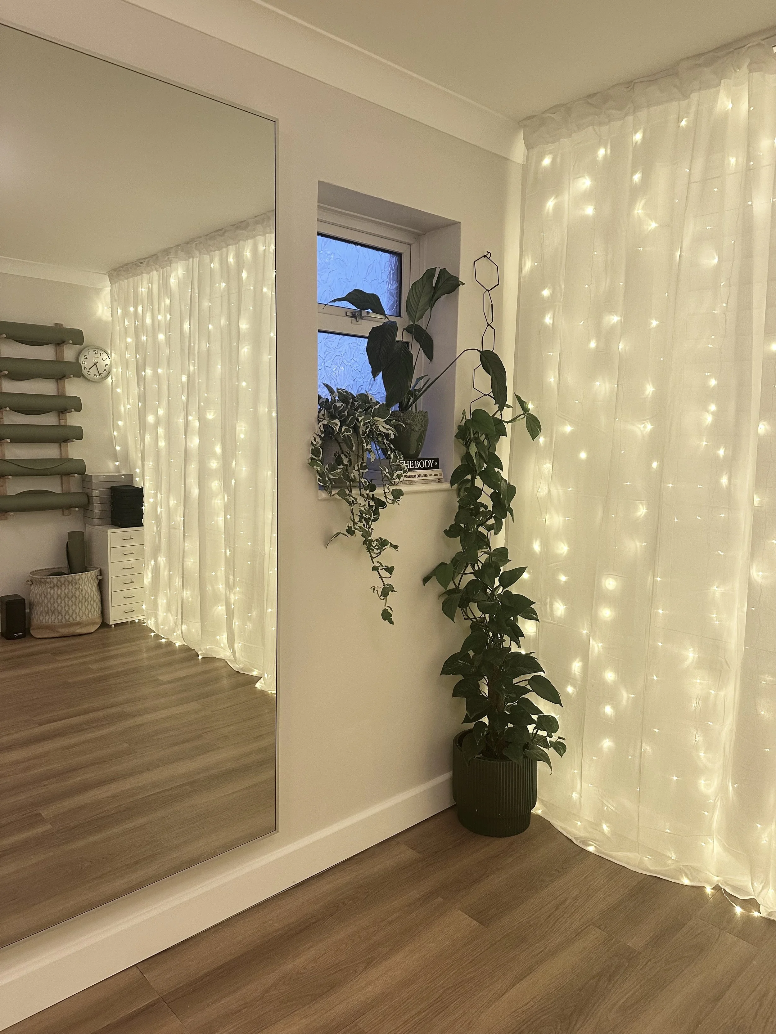 Pilates mats stored neatly, with calming fairy light curtains in the boutique pilates studio