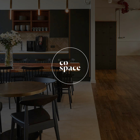 A modern kitchen and dining area with black chairs and a wooden table, with a logo that says 'co space' in the center.