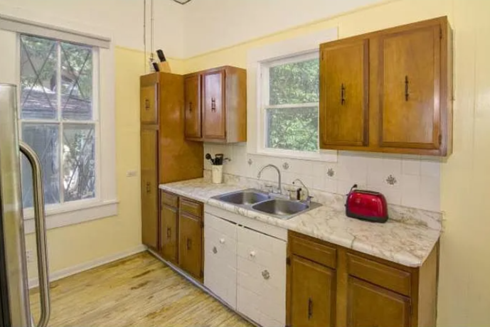 Kitchen with wooden cabinets, a marble countertop, a double sink, and a window overlooking greenery.