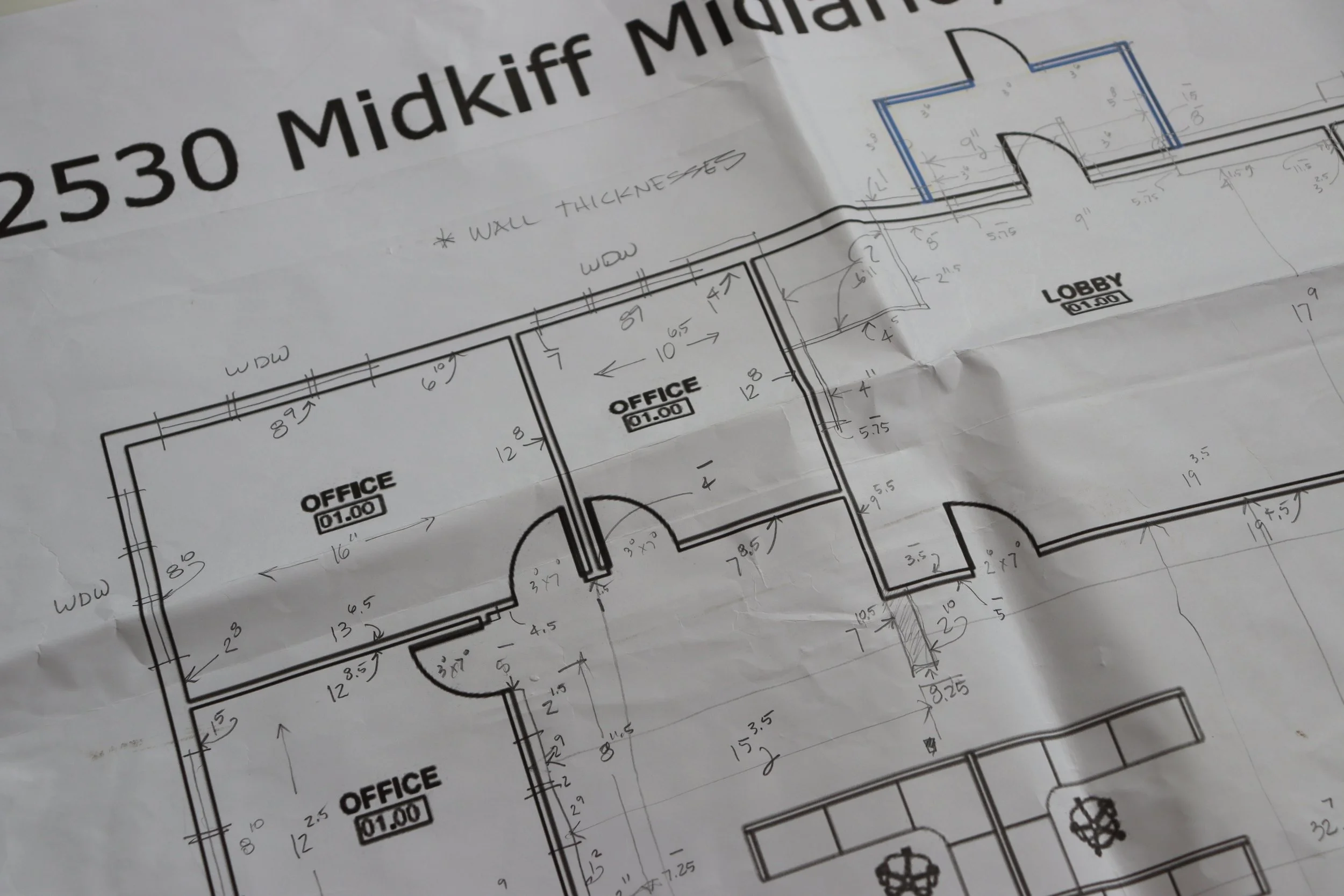 Architectural blueprint of an office building plan with multiple rooms labeled 'Office' and a lobby area, including measurements and wall thickness notes.