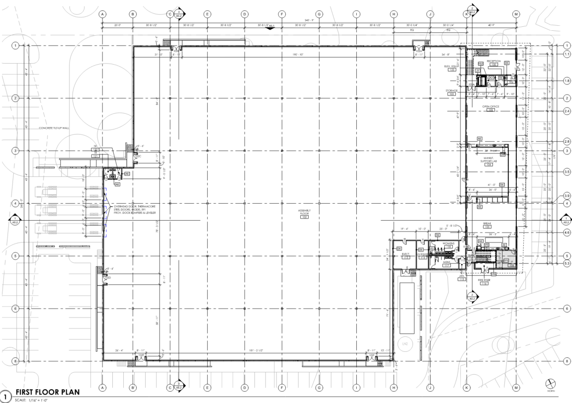 Architectural blueprint of a building's first floor plan with labeled rooms, including reception, storage, open office, mail room, women's and men's restrooms, conference room, kitchen, and various support areas, along with parking lot and exterior landscaping.
