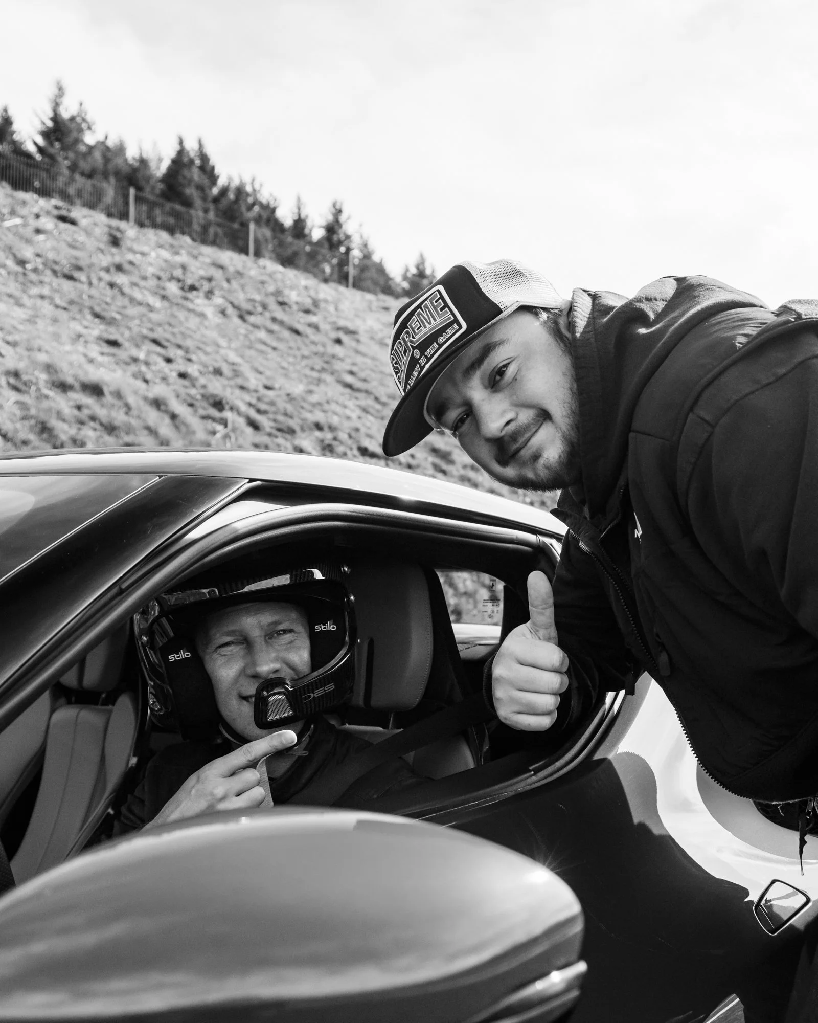Deux hommes, un dans la voiture portant un casque de pilote et l'autre dehors