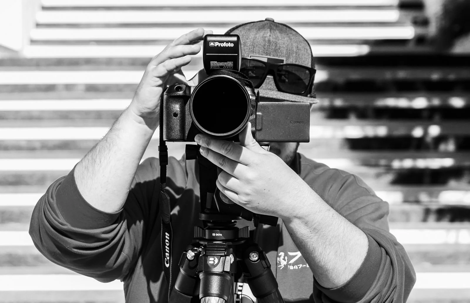 Photographe professionnel en plein cadrage avec un appareil photo reflex et utilisant un trépied.