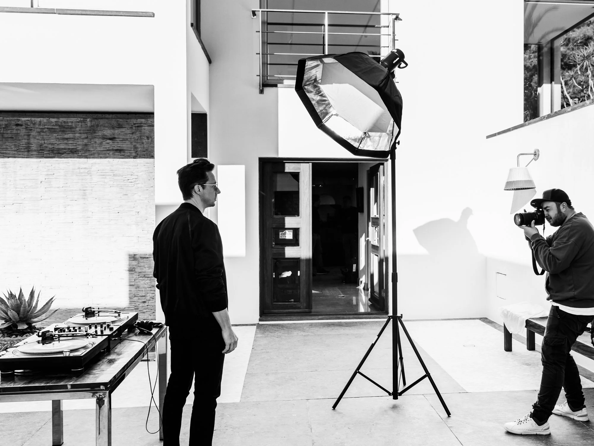 Une séance photo en extérieur avec un homme posant, un photographe prenant une photo, un studio avec un éclairage, une table de DJ