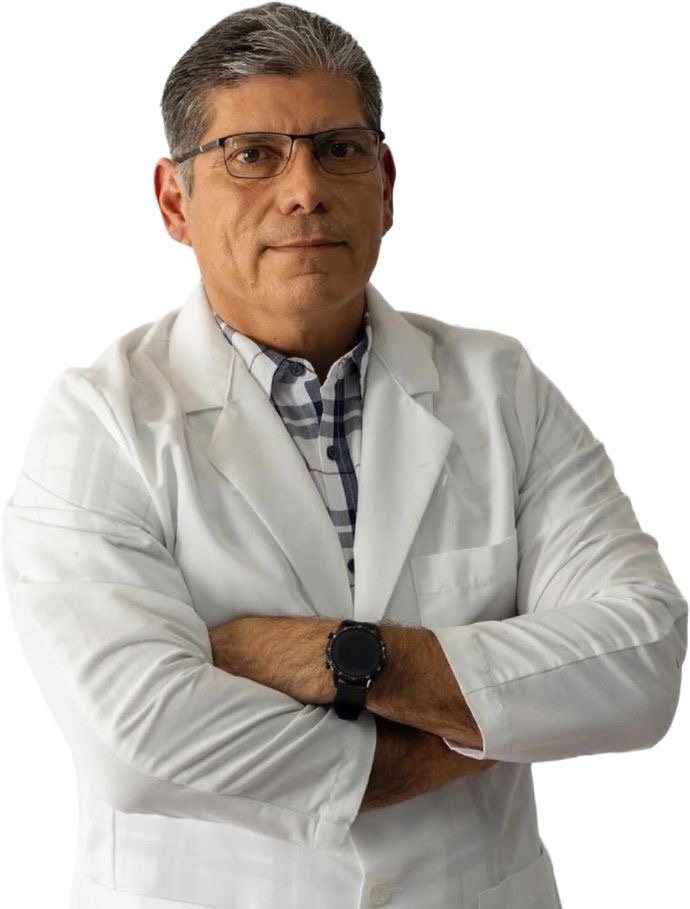 Hombre con bata blanca y gafas, con los brazos cruzados, en frente de fondo blanco.