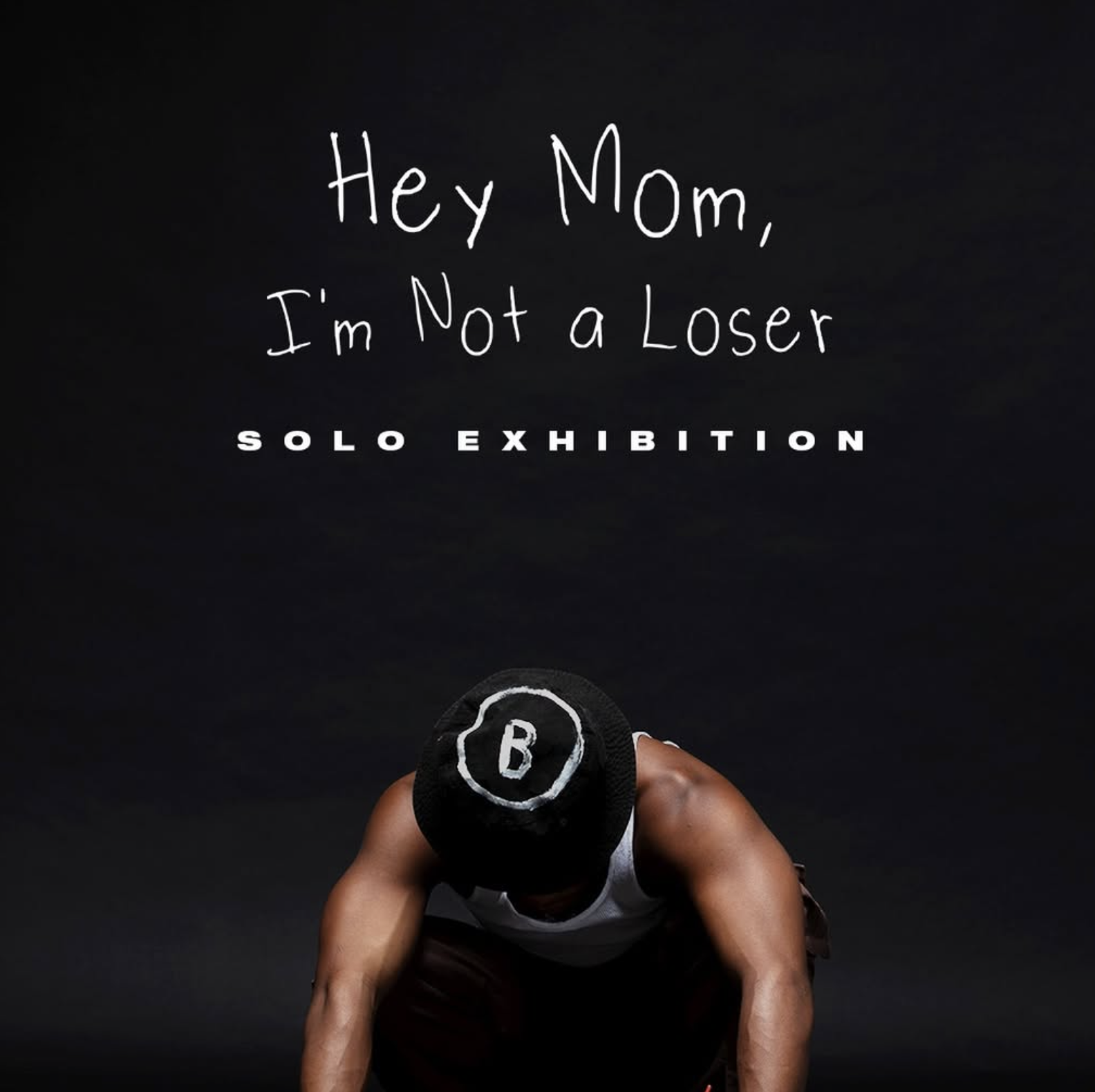 A person in athletic attire with a cap bent down on a black background, holding a weight plate with the letter B visible.