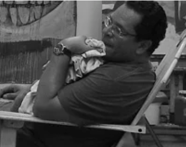 A man sitting in a chair, holding a baby.