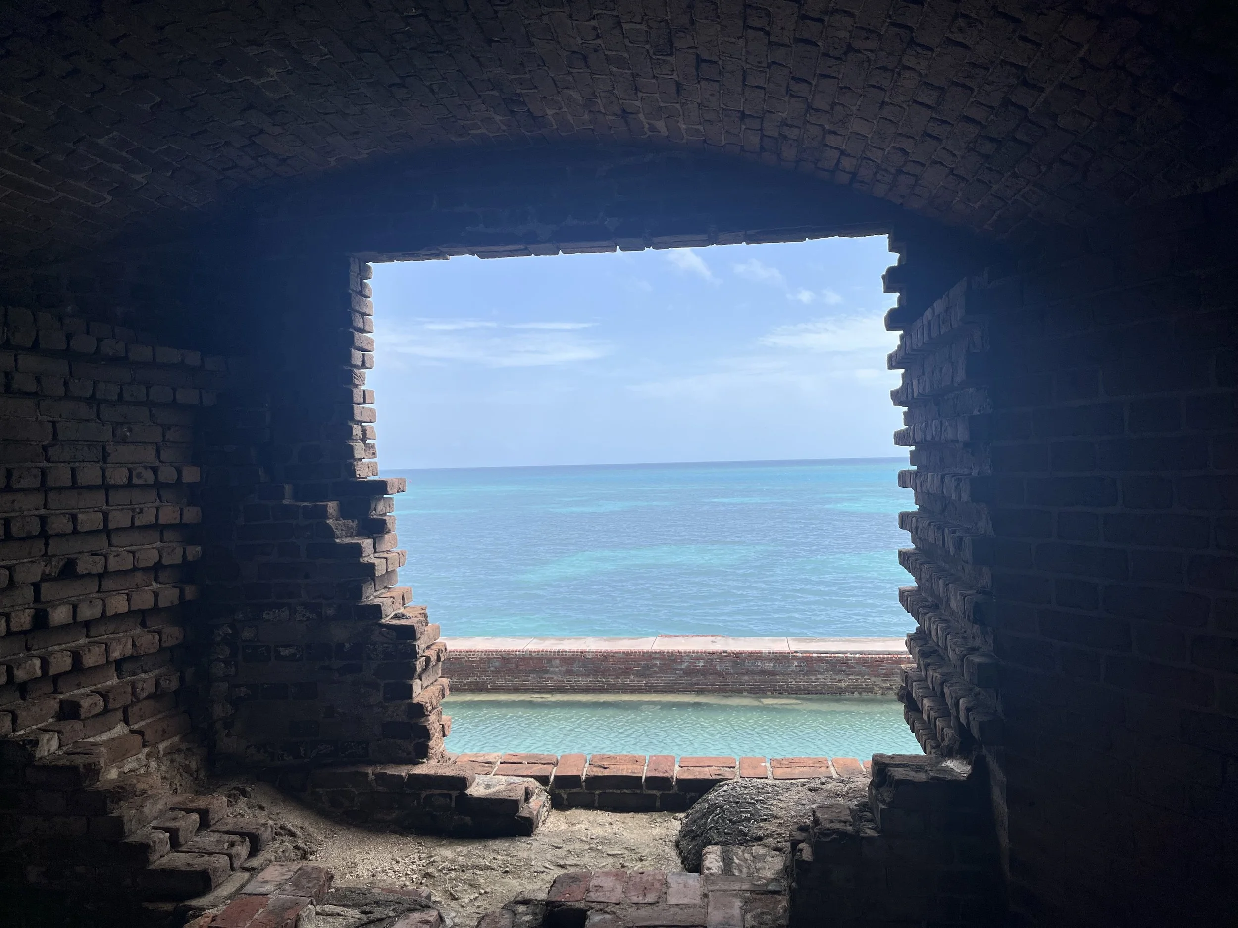 View of a bright blue ocean and sky through a rectangular opening in a brick structure, Fort Jefferson, Dry Tortugas National Park.