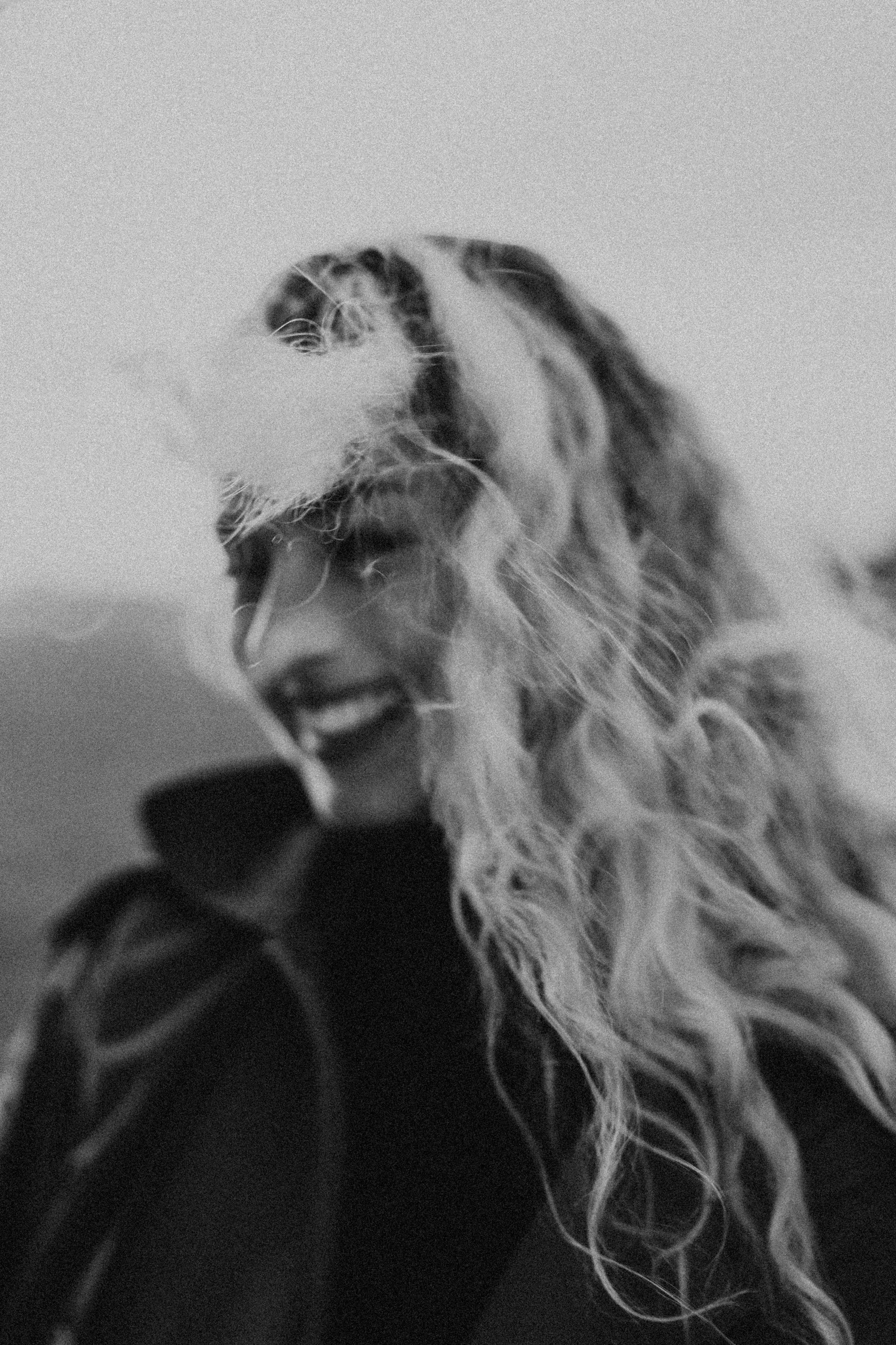 Black and white portrait of a woman smiling in the wind, reflecting the freedom and intention behind thoughtfully designed therapy office spaces.