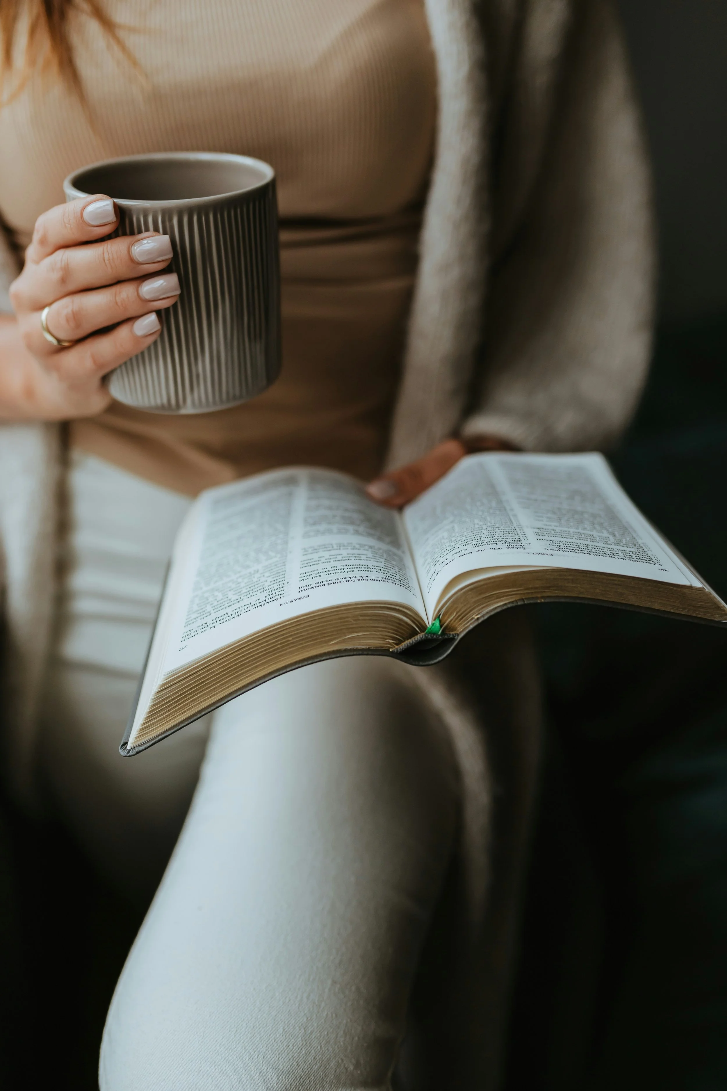 Therapist enjoying a quiet moment with coffee and a book in a calming therapy office space designed to support the sacred work of healing.